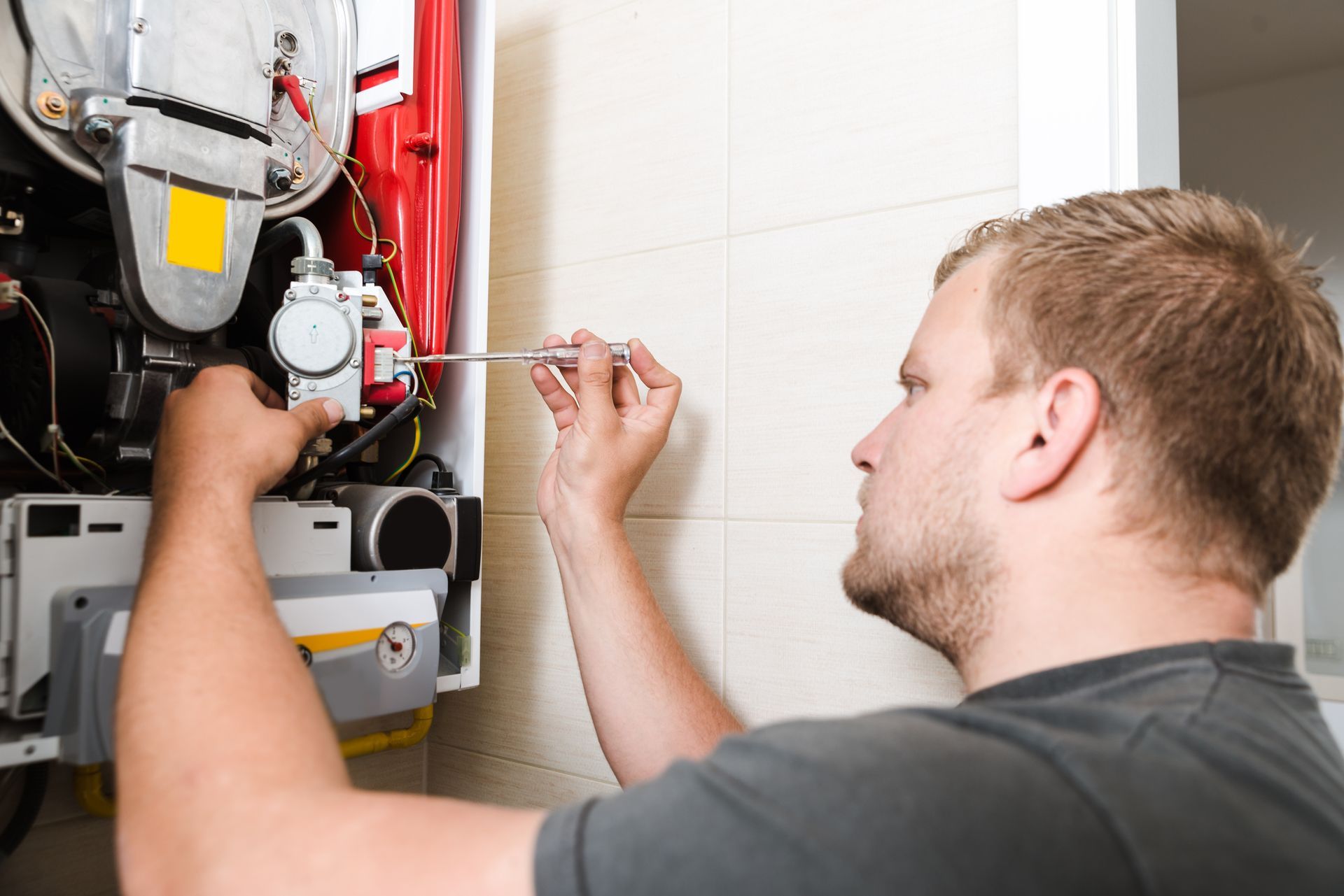 Person repairing a gas furnace with a wrench. Person repairing a gas furnace with a wrench.