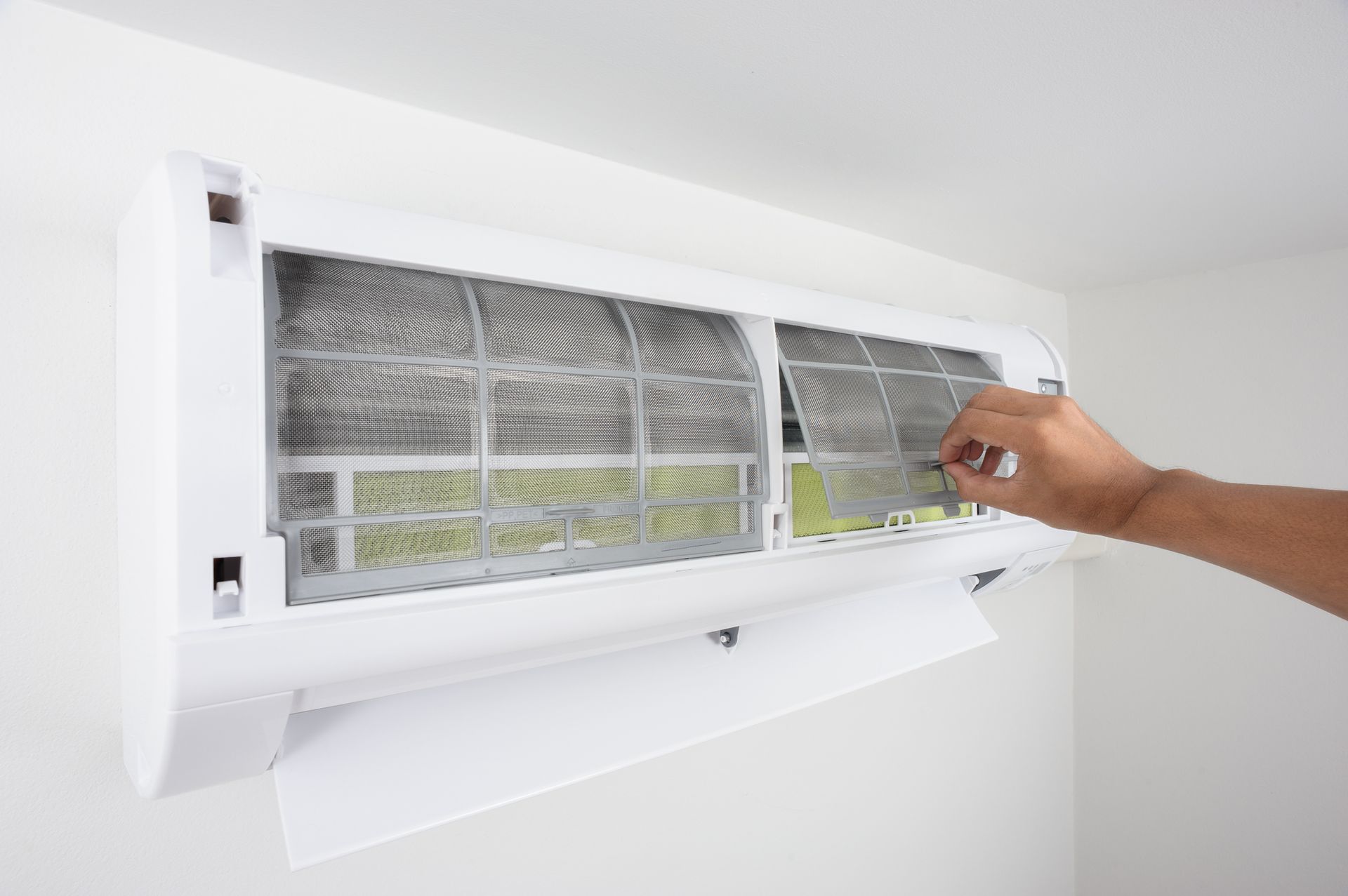 Hand cleaning air conditioner filter during HVAC maintenance for better airflow.