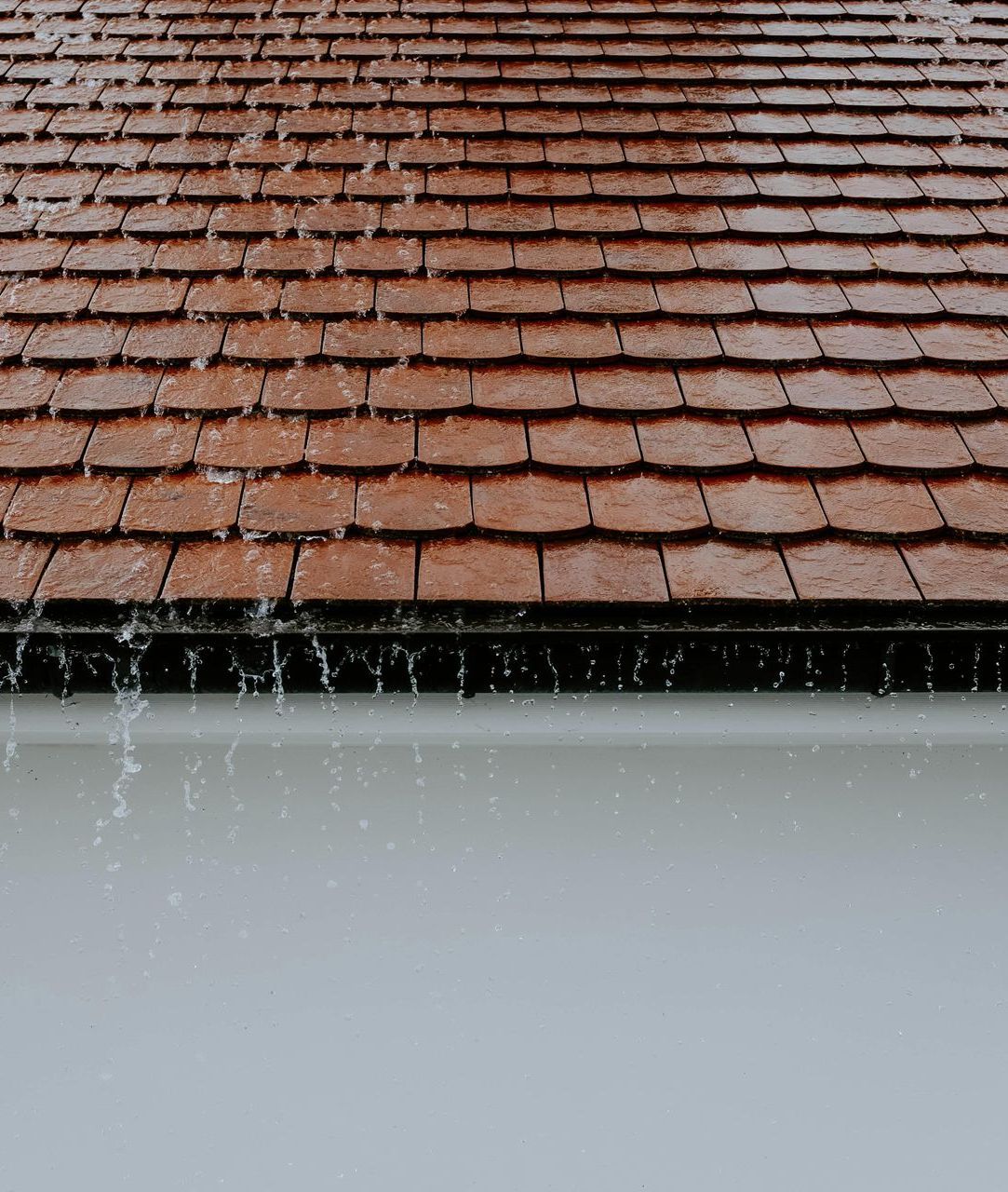 Rain is falling on a red tiled roof.