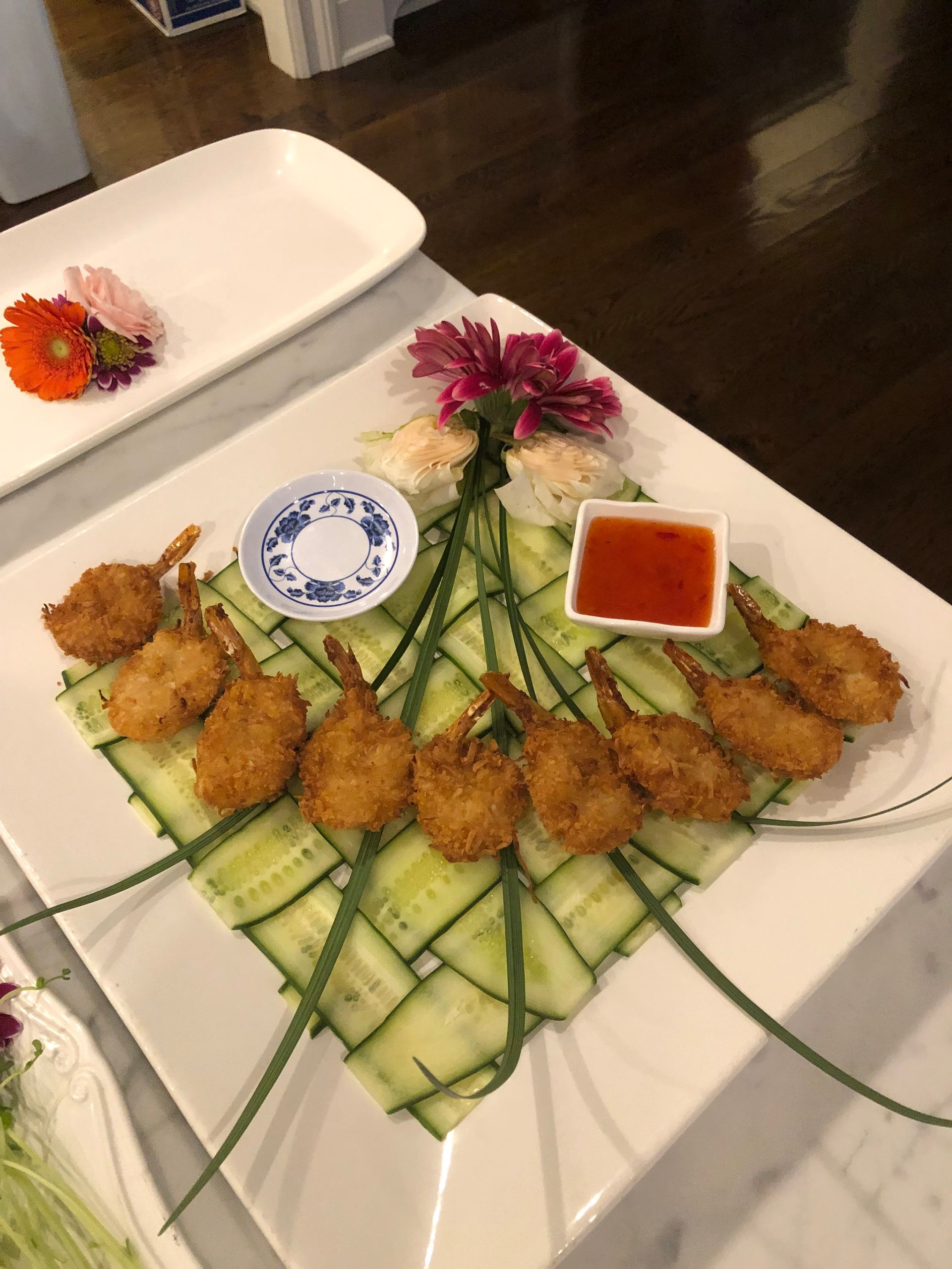 Fried shrimp arranged on cucumber lattice with dipping sauces and flowers.