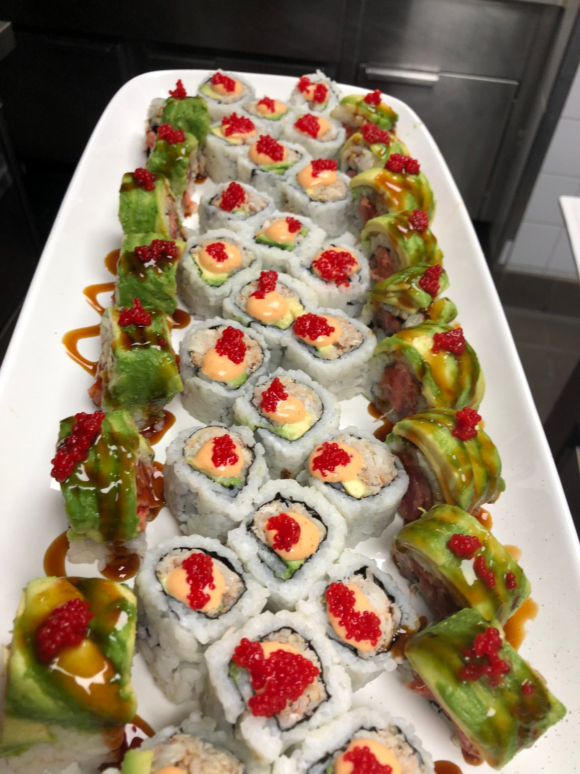 Sushi platter with various rolls, toppings, and sauces.