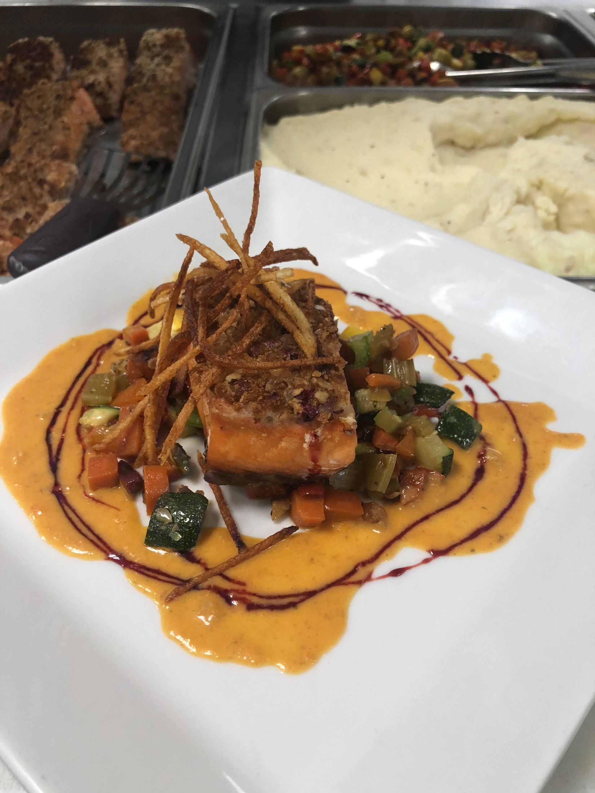 Salmon with vegetable medley and sauce, on a white plate.