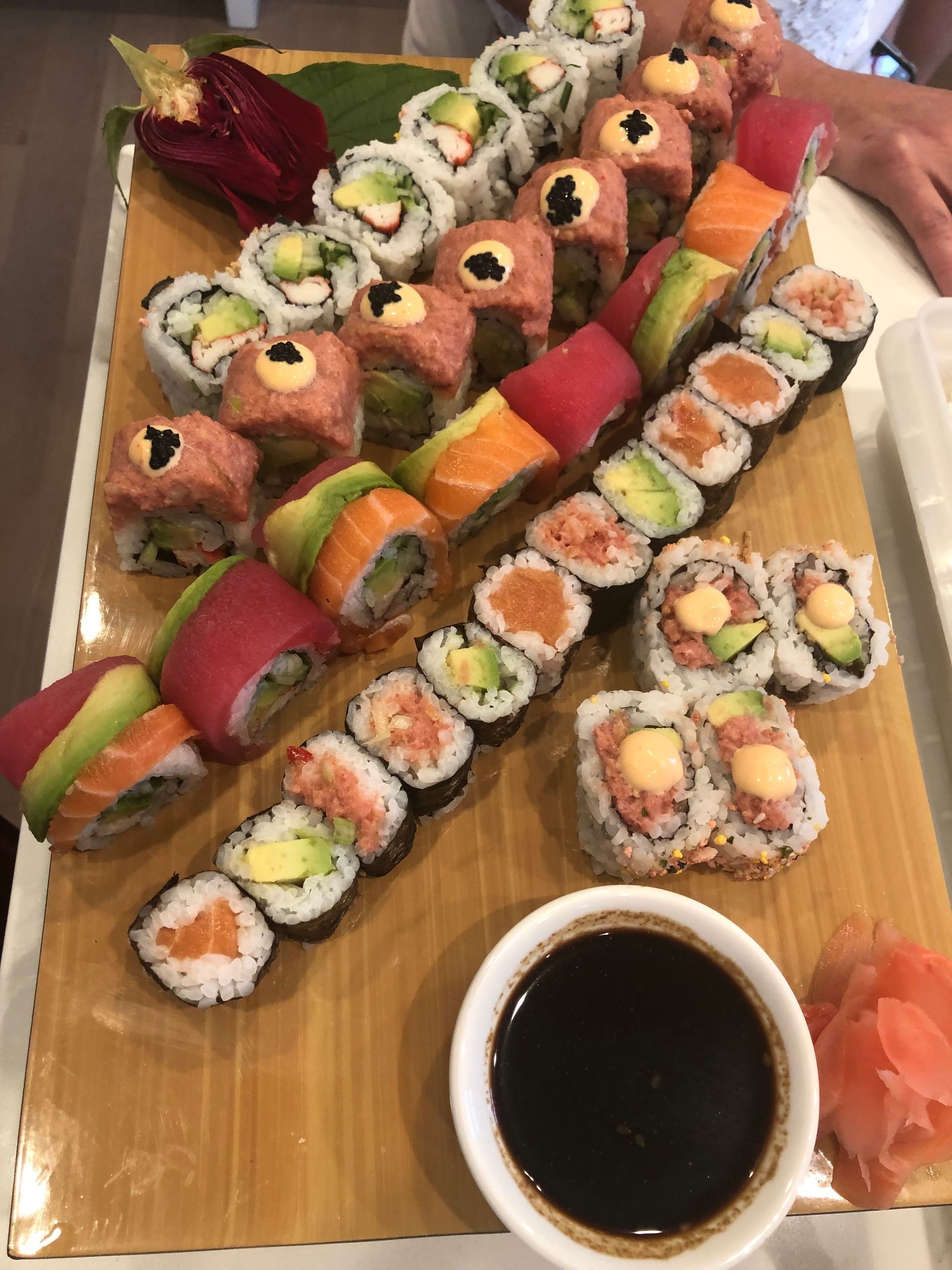 Sushi platter with various rolls, soy sauce, and pickled ginger.