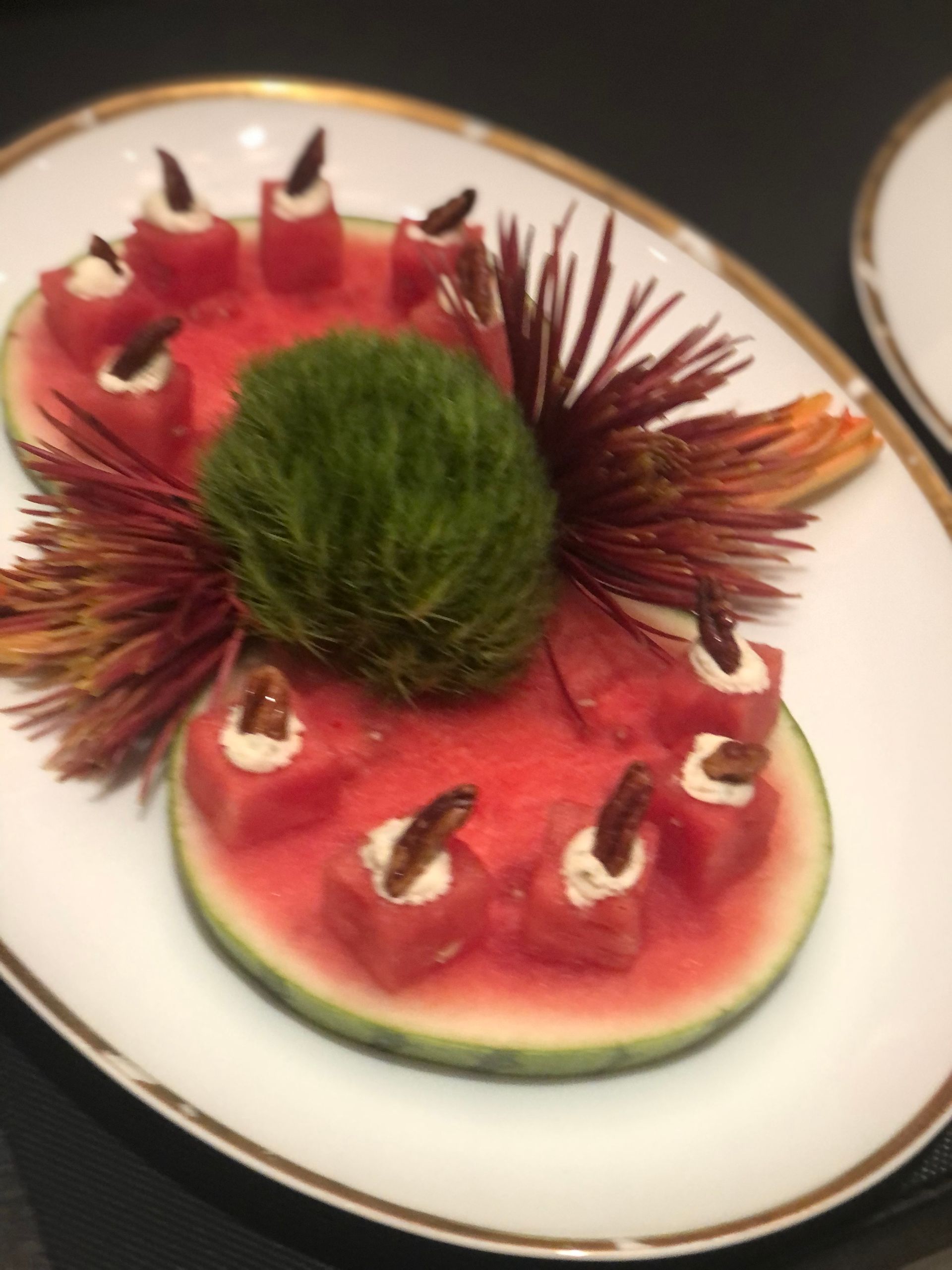 Watermelon slices with decorative toppings and a green central decoration, on a white plate.