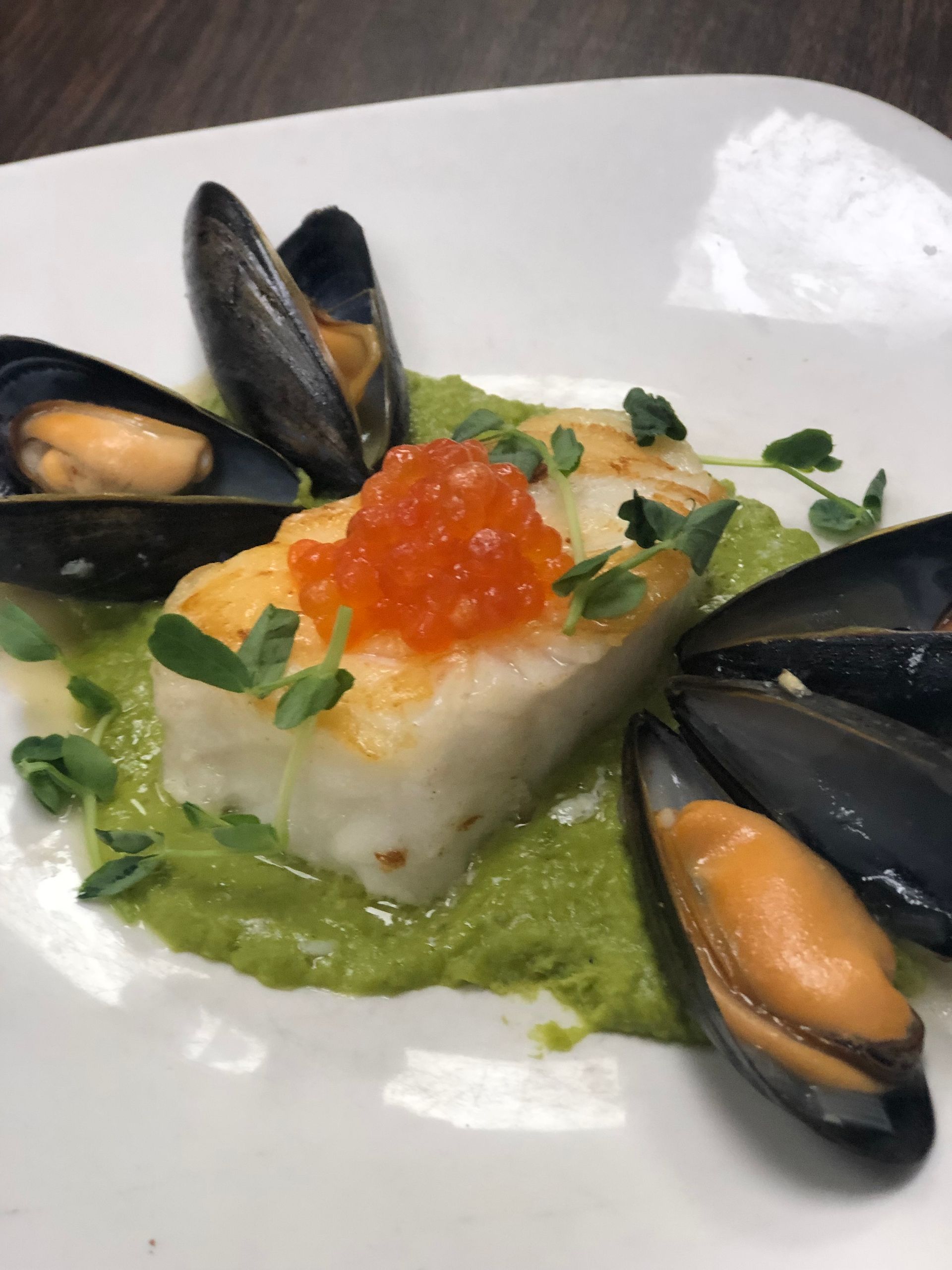 Seared white fish on pea puree, topped with red roe, surrounded by mussels.
