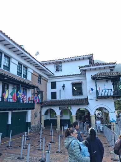 Edificio con entrada arqueada, banderas y gente haciendo cola.