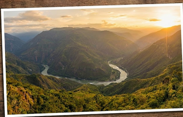 Río que serpentea a través de un terreno verde y montañoso, iluminado por una cálida puesta de sol.
