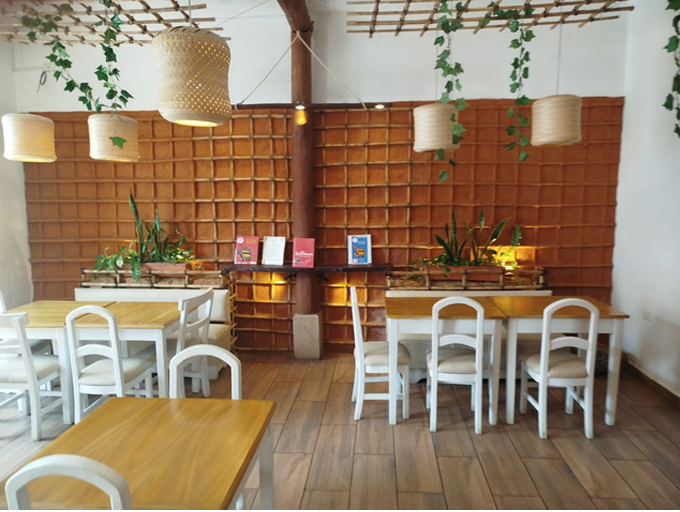 Comida frita en un recipiente oscuro, rociada con salsa blanca y guarnición de eneldo.