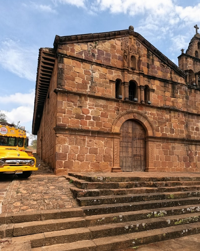 Iglesia de piedra con escalones y un autobús escolar amarillo.