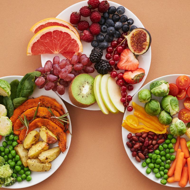 Three plates of fruits and vegetables on a table