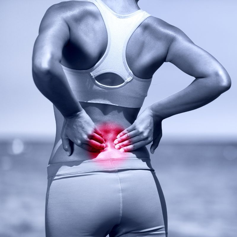 A woman is holding her lower back in pain
