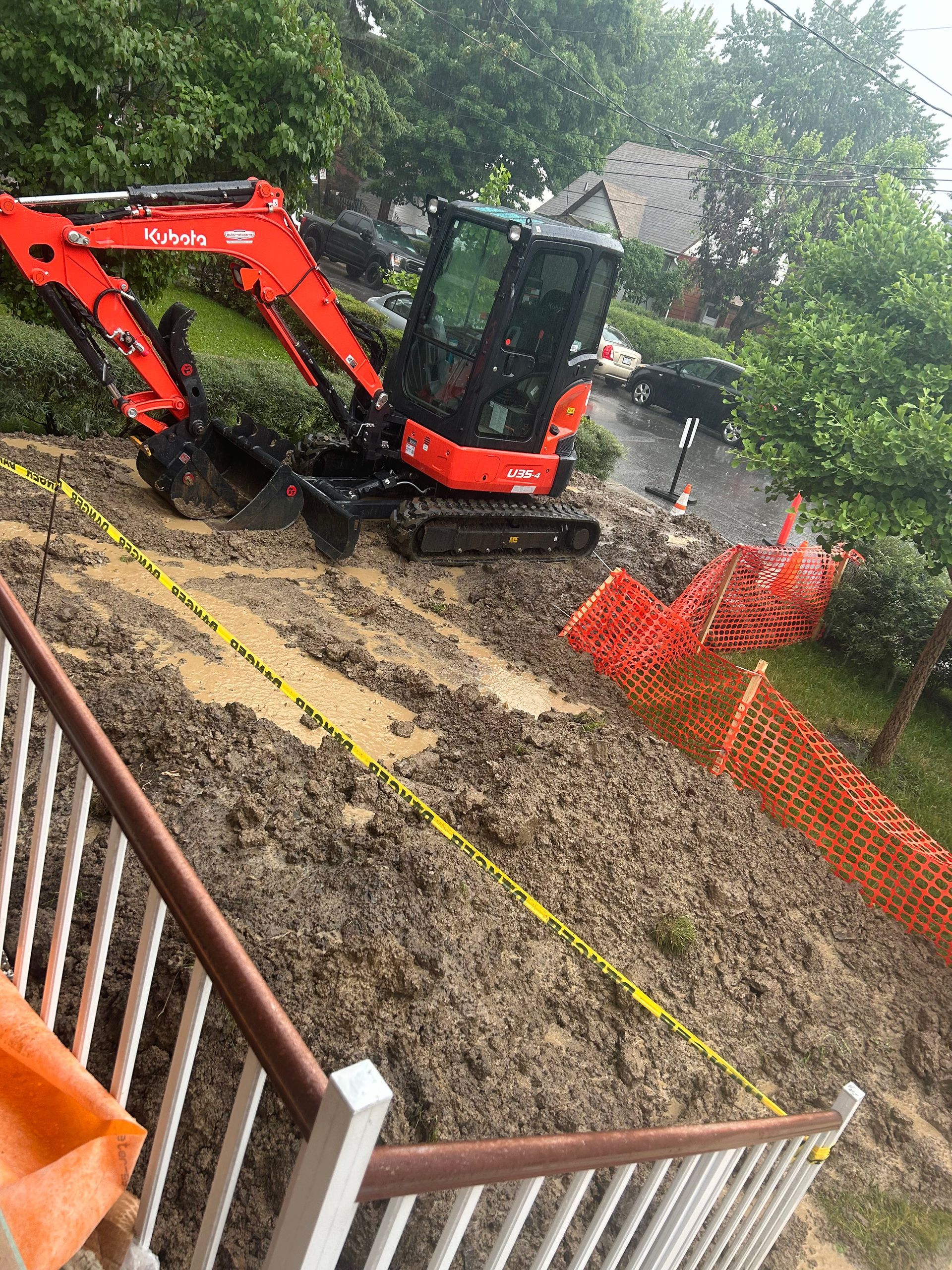 Une excavatrice rouge et noire est assise au sommet d'une colline boueuse.