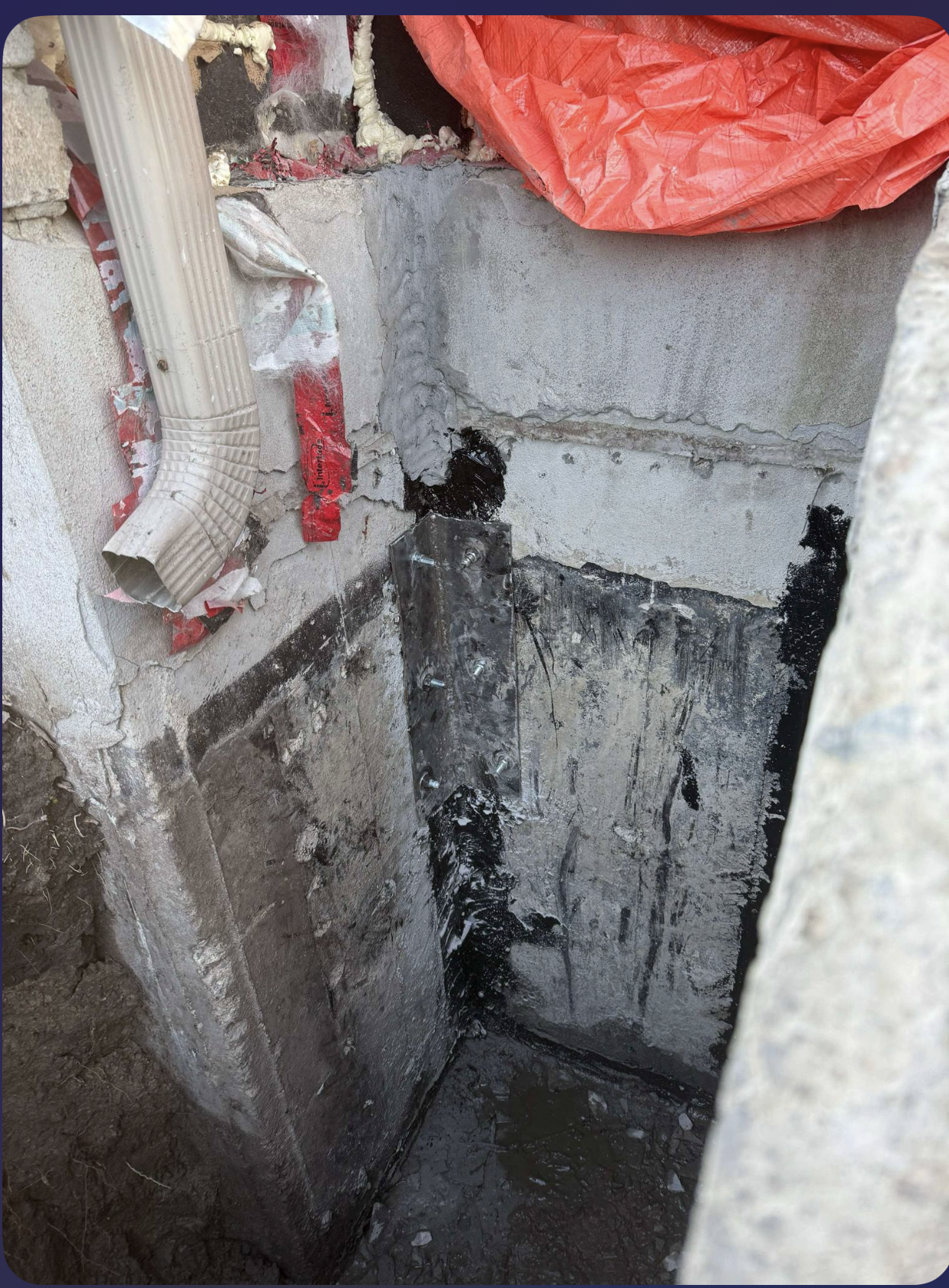 Un mur en béton avec un trou dedans et une bâche rouge dessus.