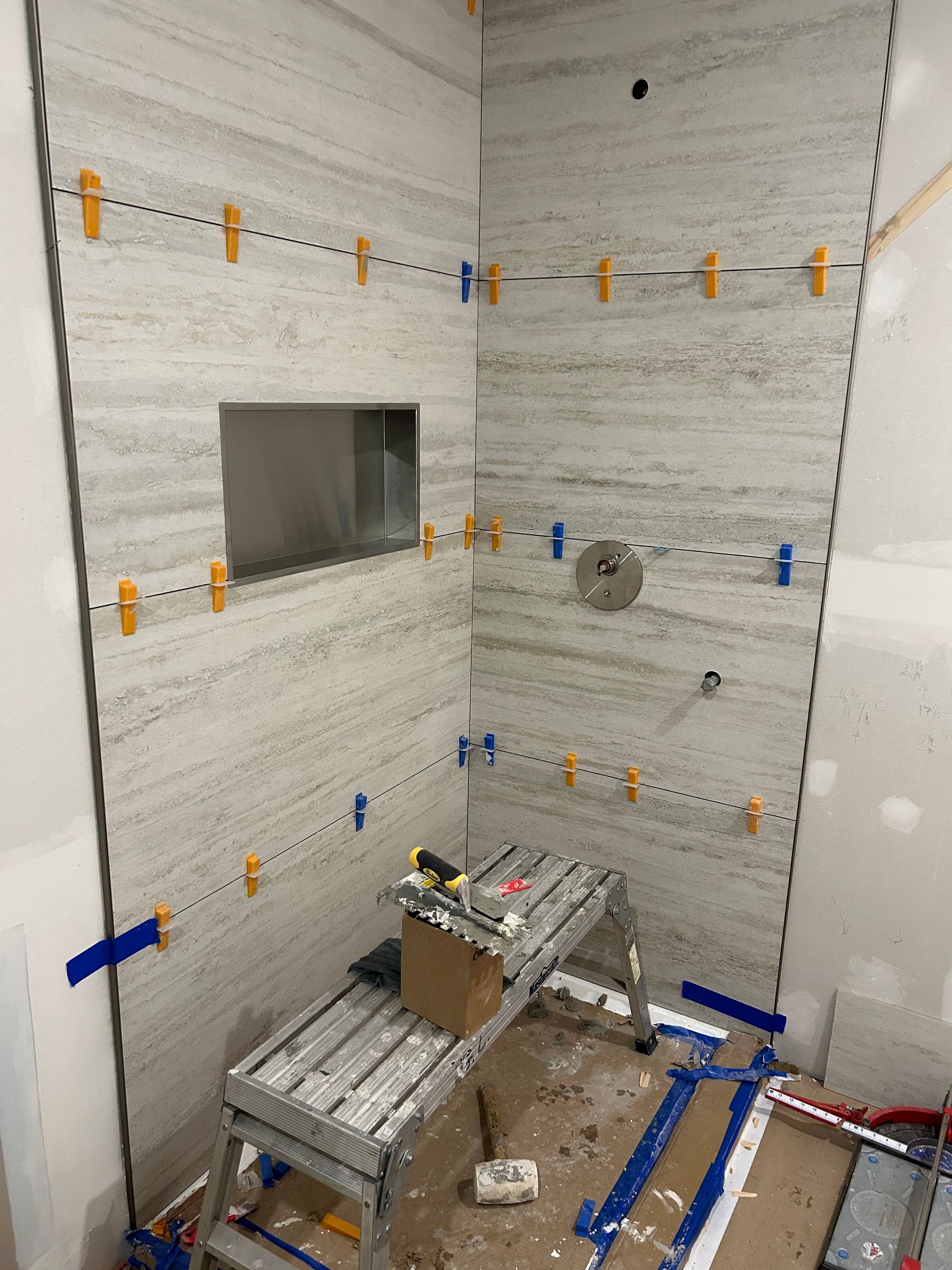 Une salle de bain en construction avec un banc et une boîte au sol.