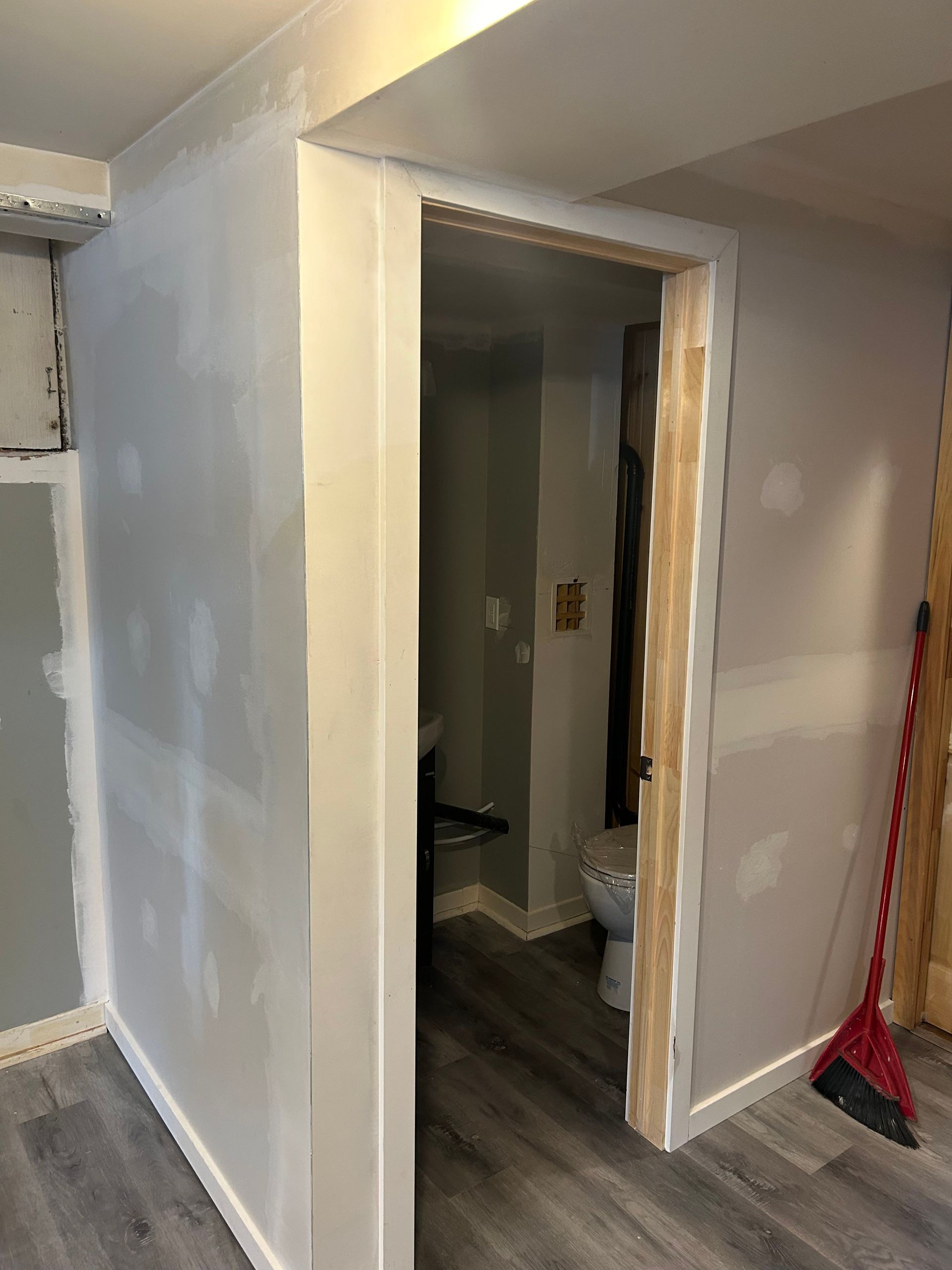 Une pièce avec des toilettes et un balai dedans.