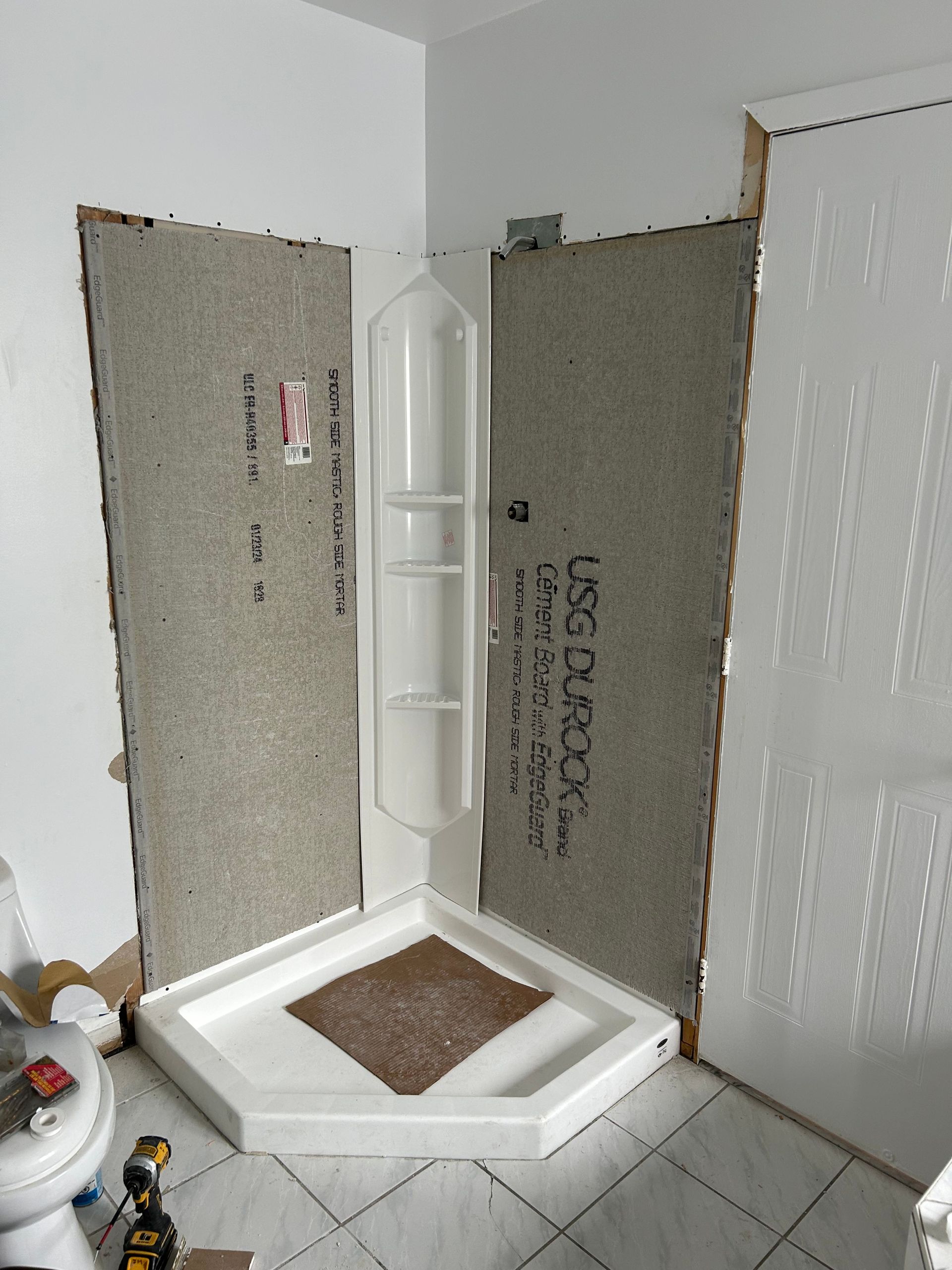 Une cabine de douche est en cours de construction dans une salle de bain.