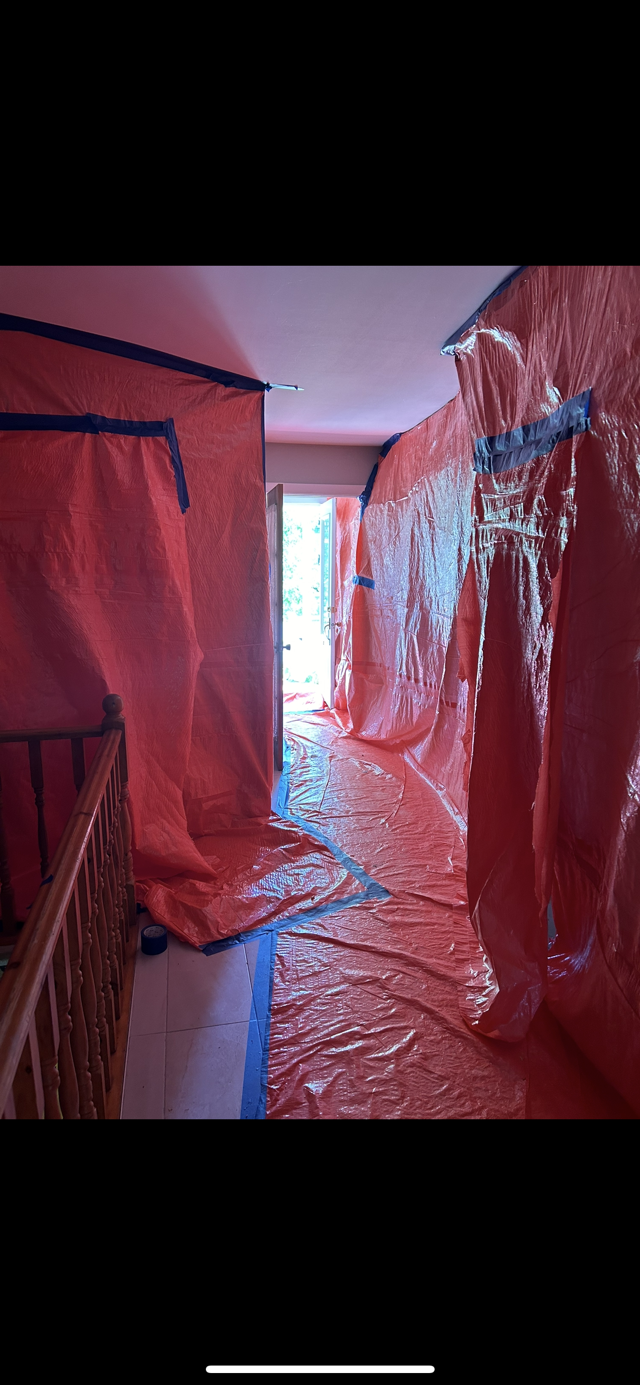 Un couloir dans une maison recouvert de bâches en plastique.