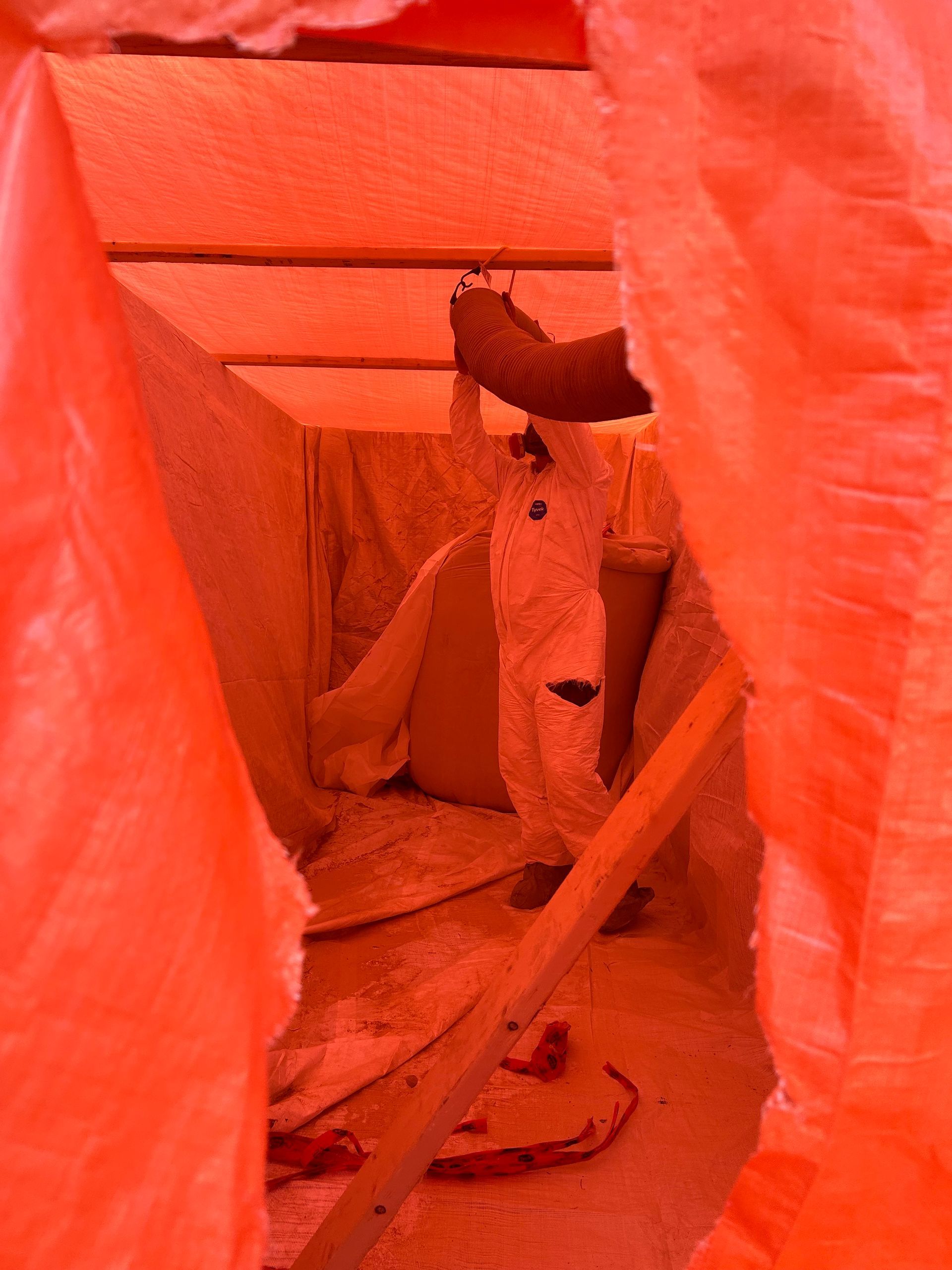 Un homme en costume blanc se tient debout dans une tente orange.