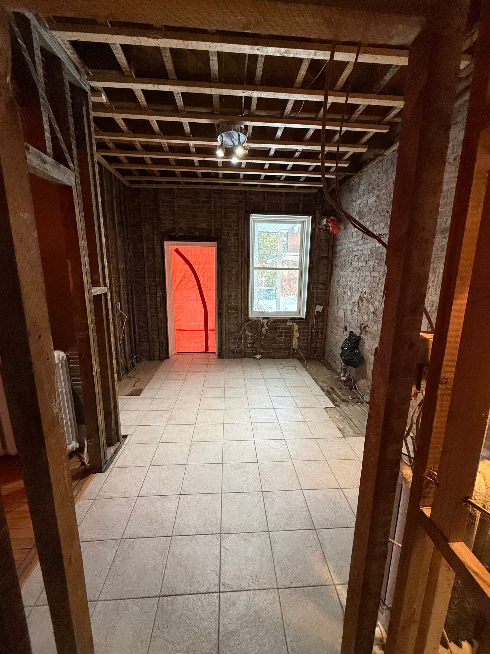 Une pièce avec une porte rouge et une fenêtre est en cours de rénovation.