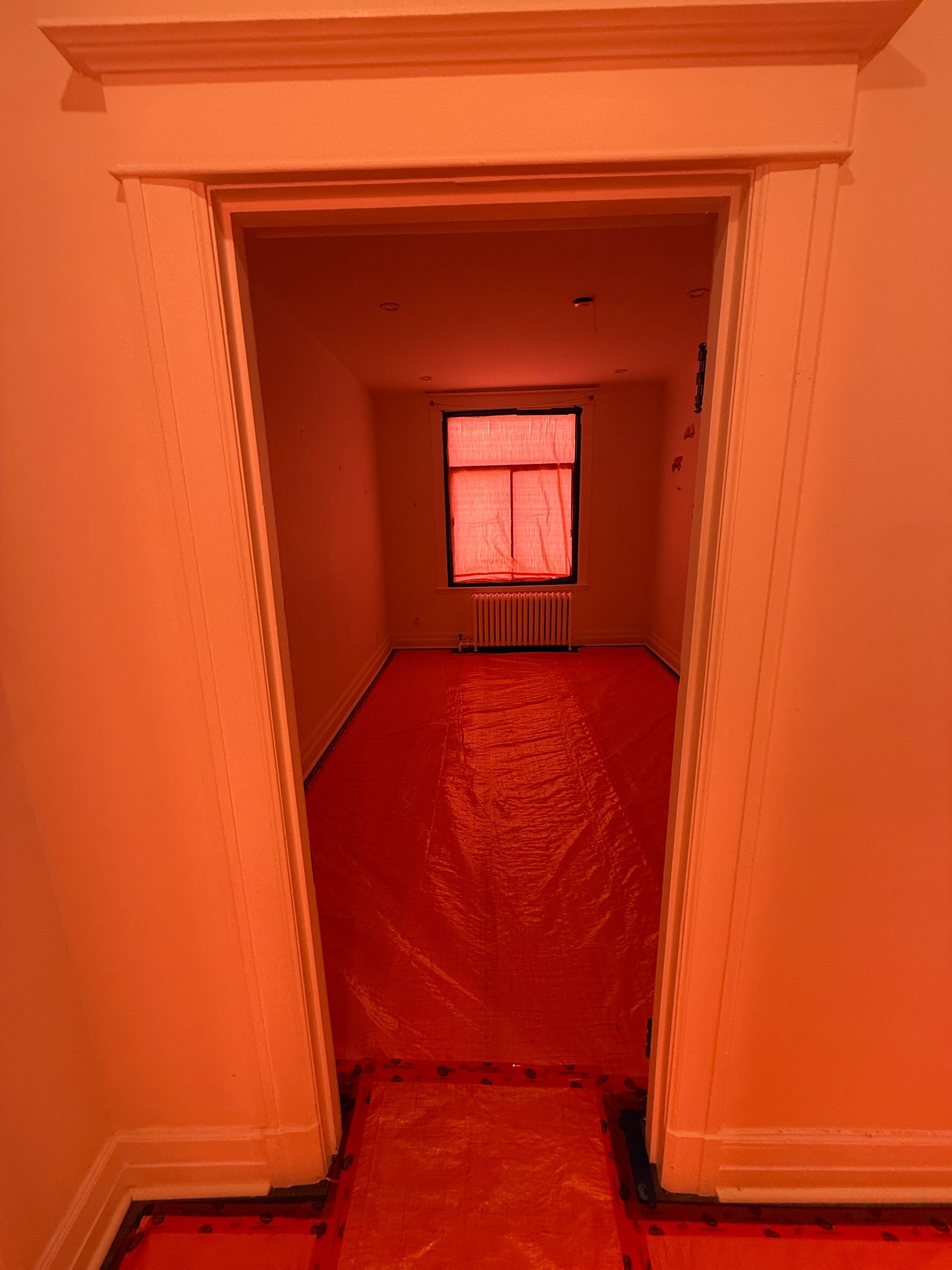 Une pièce avec une bâche rouge sur le sol et une fenêtre.