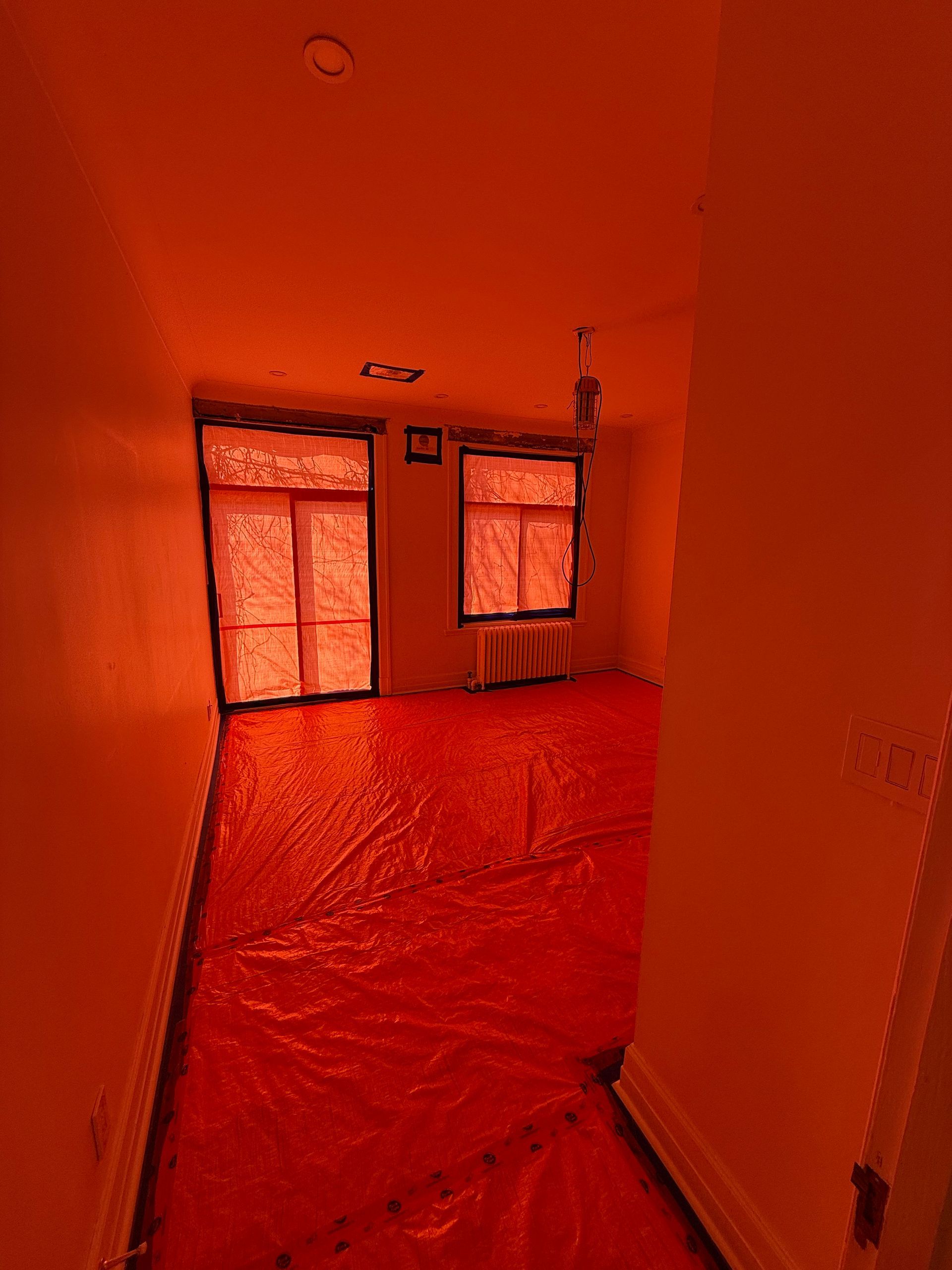 Une pièce vide avec une bâche rouge sur le sol et les murs.