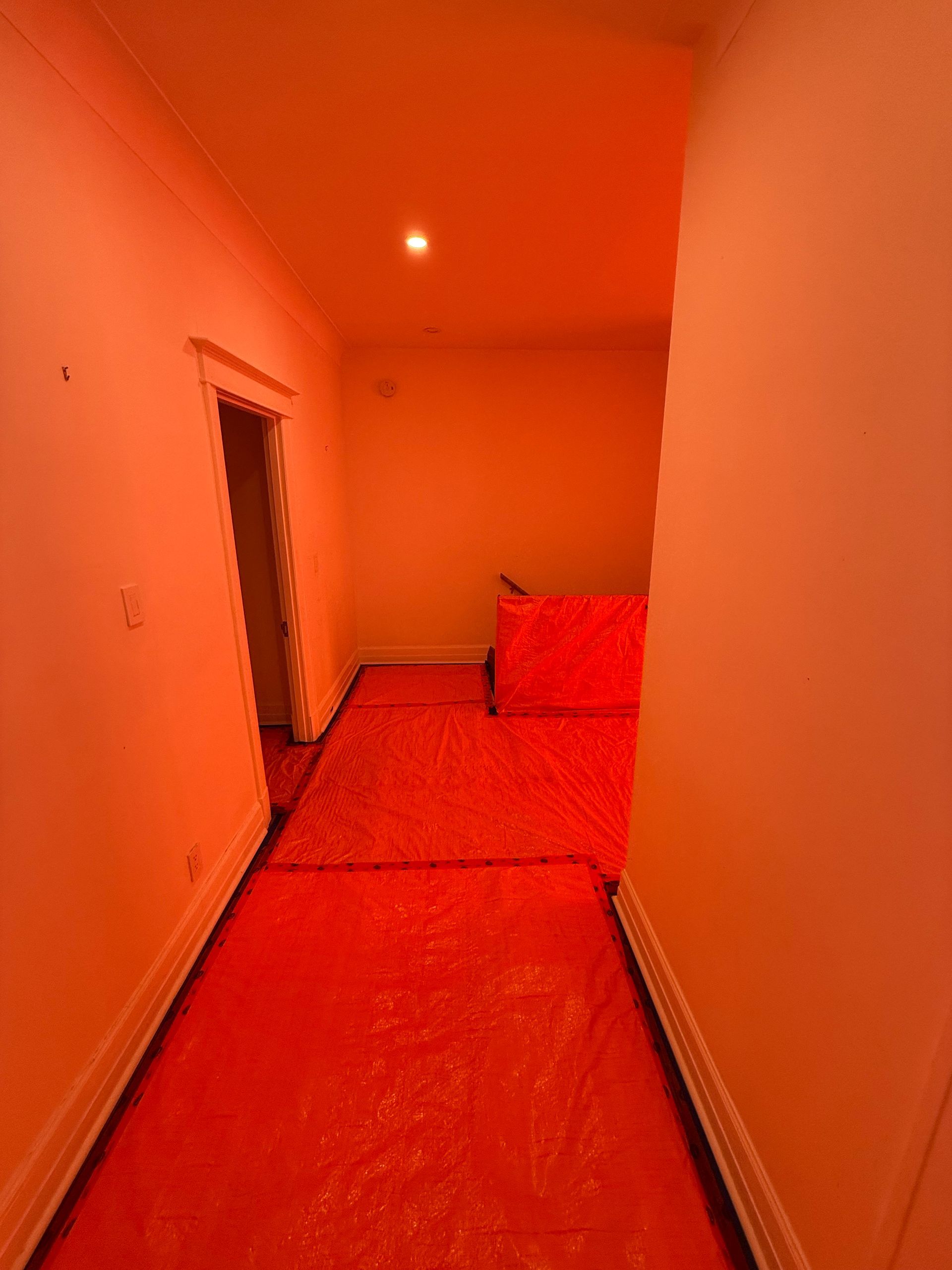 Un couloir avec un canapé rouge et une bâche rouge sur le sol.