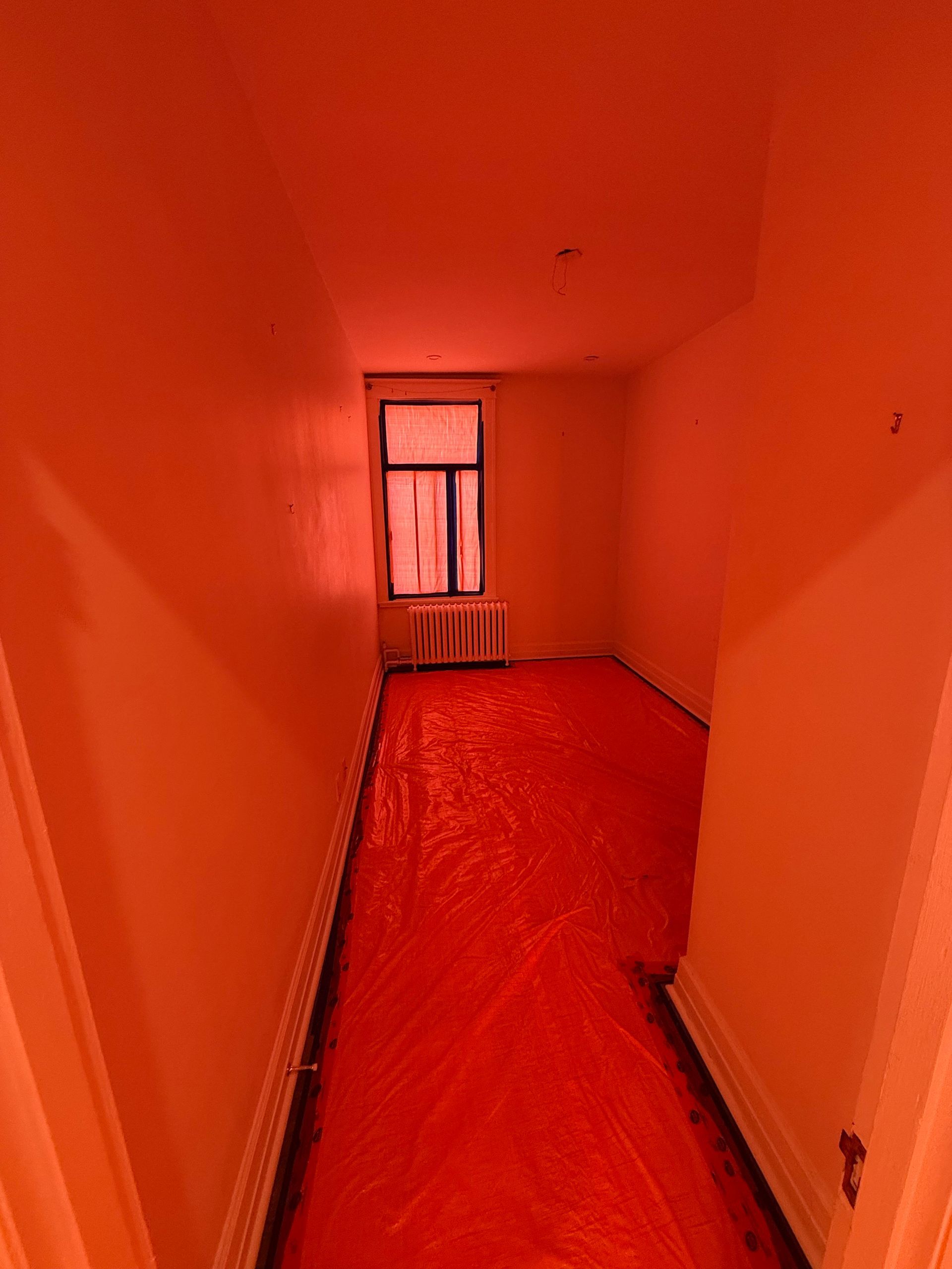 Une pièce vide avec une bâche rouge sur le sol et une fenêtre.