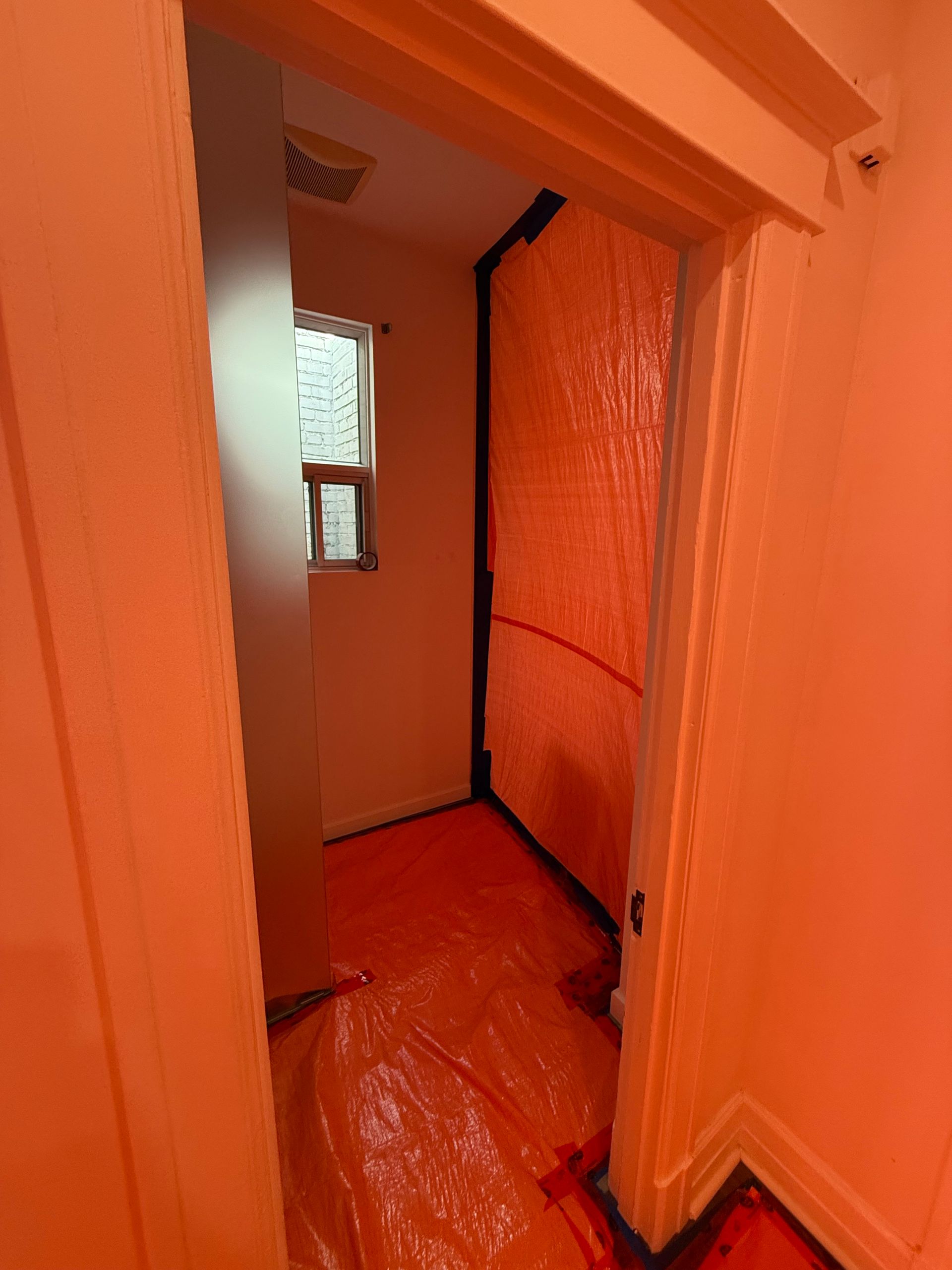 Une porte menant à une pièce avec du plastique orange sur le sol