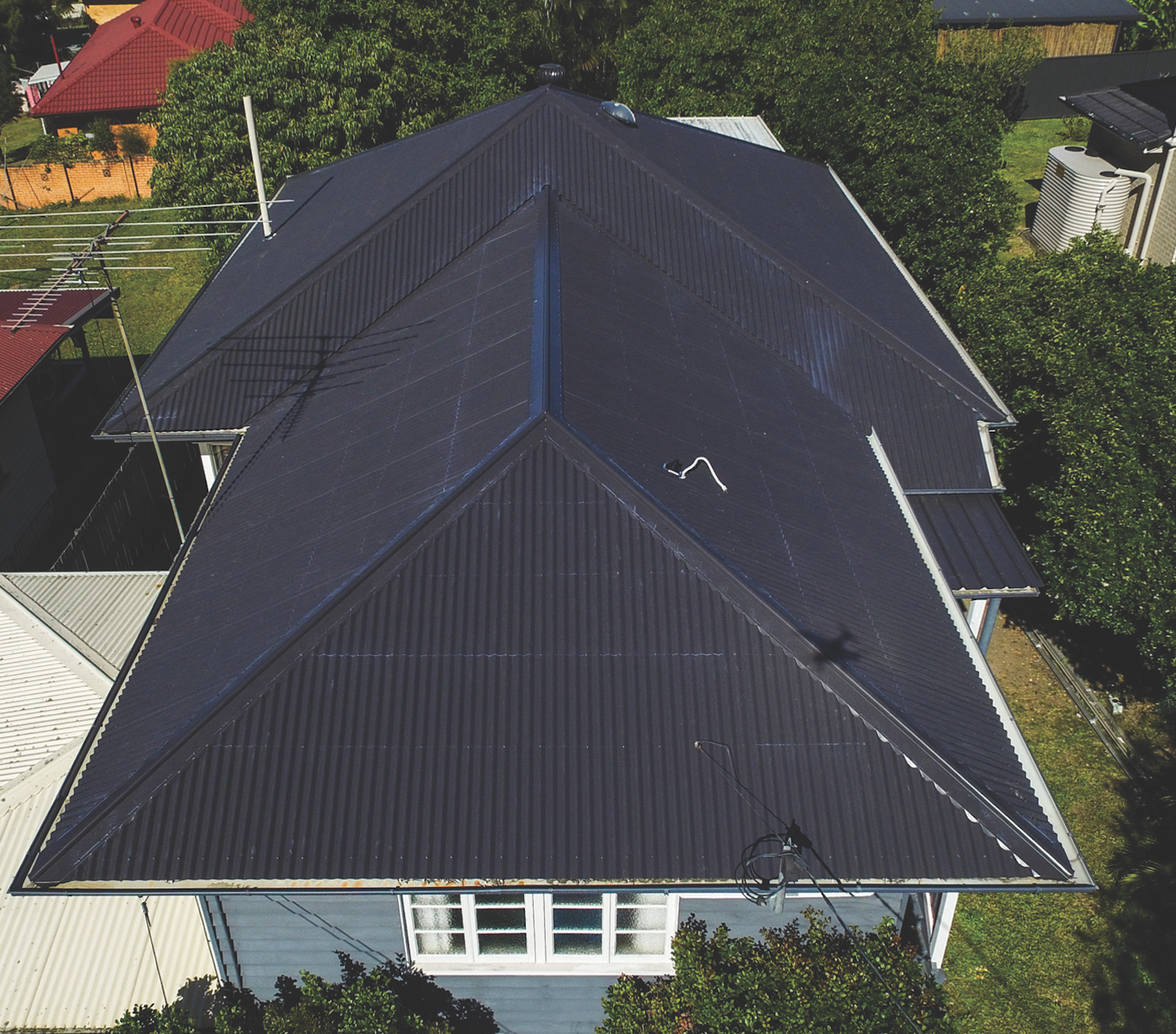 Aerial view of a house with a red roof and rooftop solar panels.