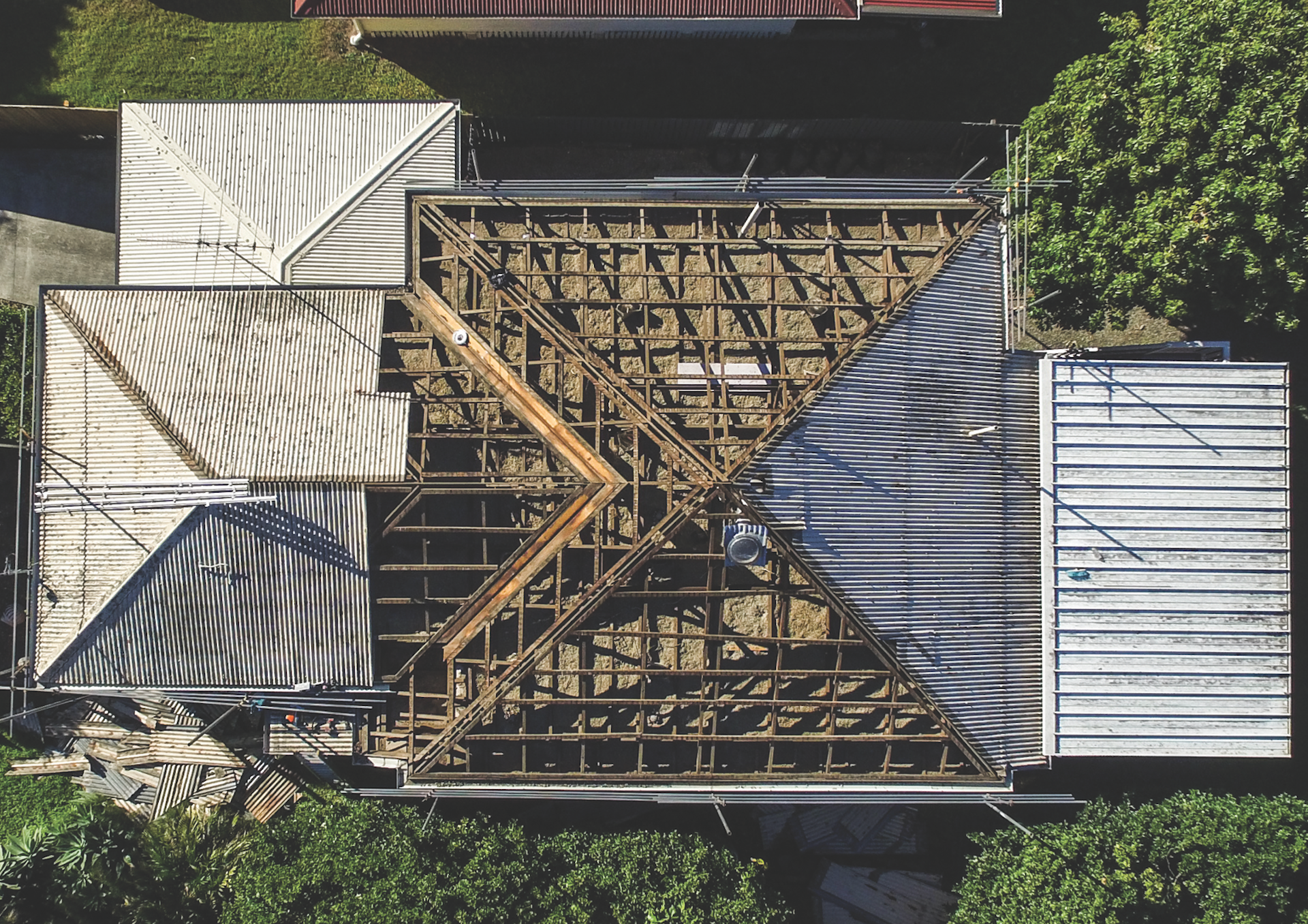 Aerial view of a house roof under construction with exposed wooden framing and metal roofing panels.