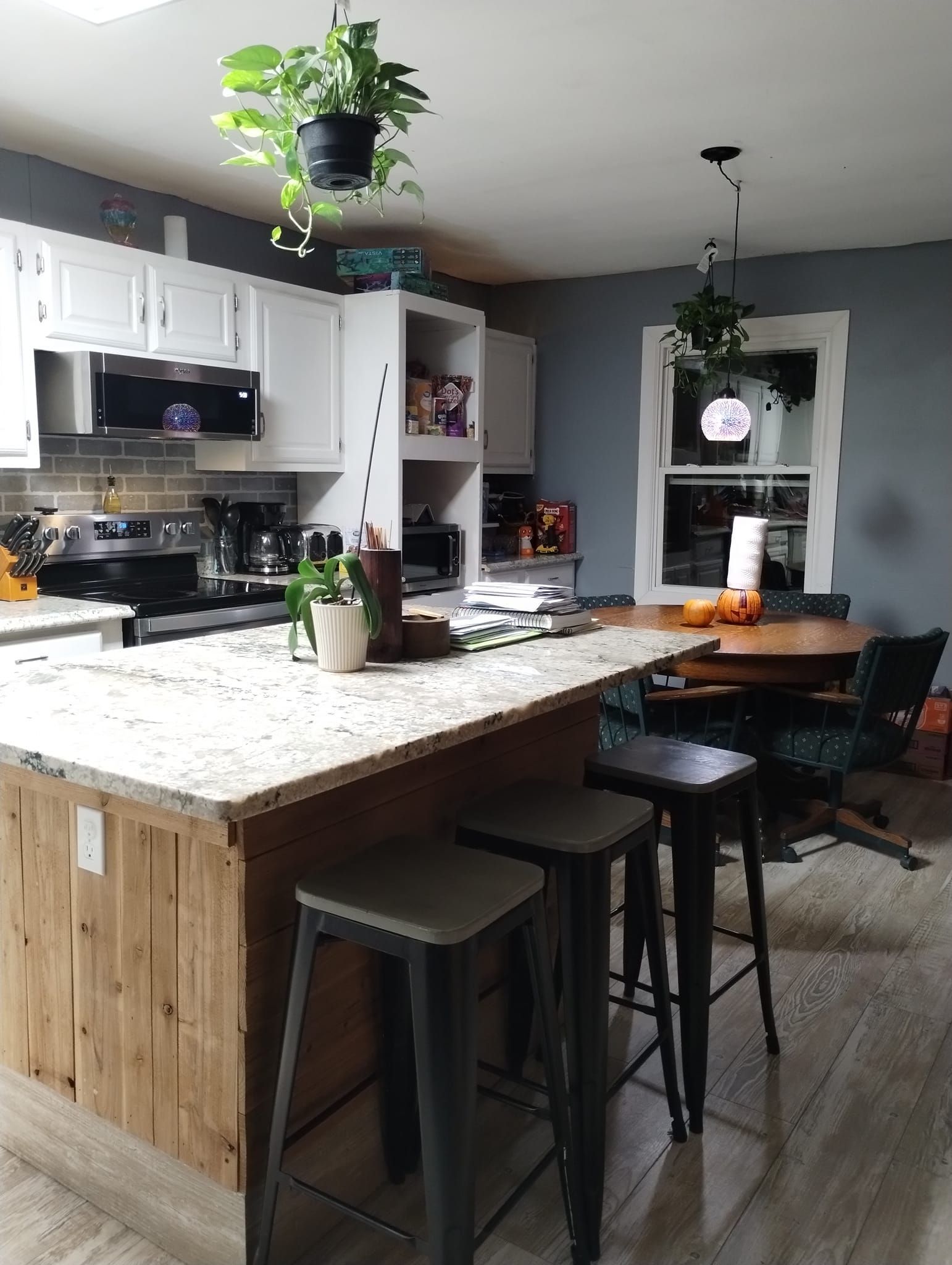 Kitchen with white cabinets, wood island, and hanging plants.