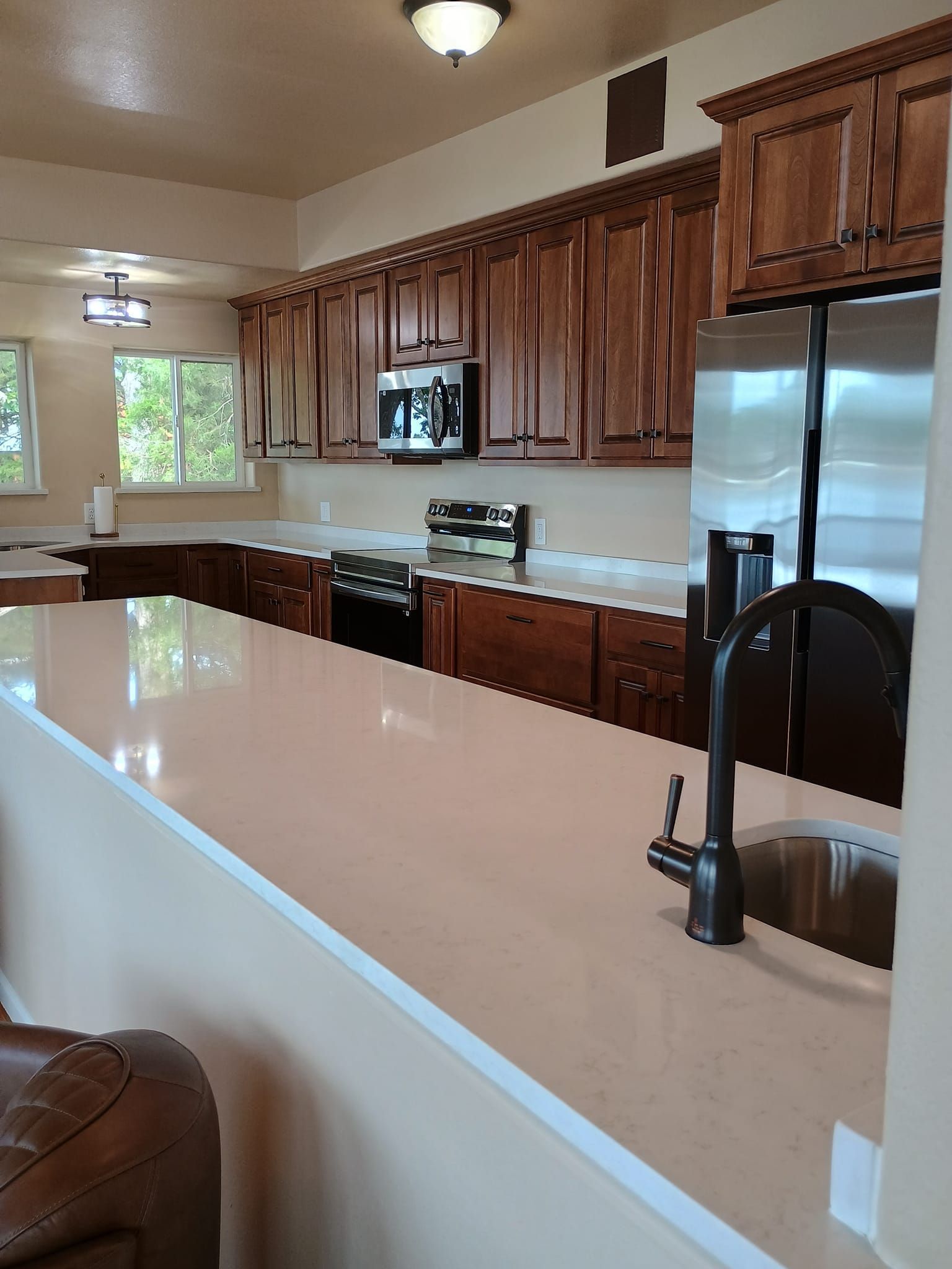 Kitchen with light countertops, dark wood cabinets, and stainless steel appliances.