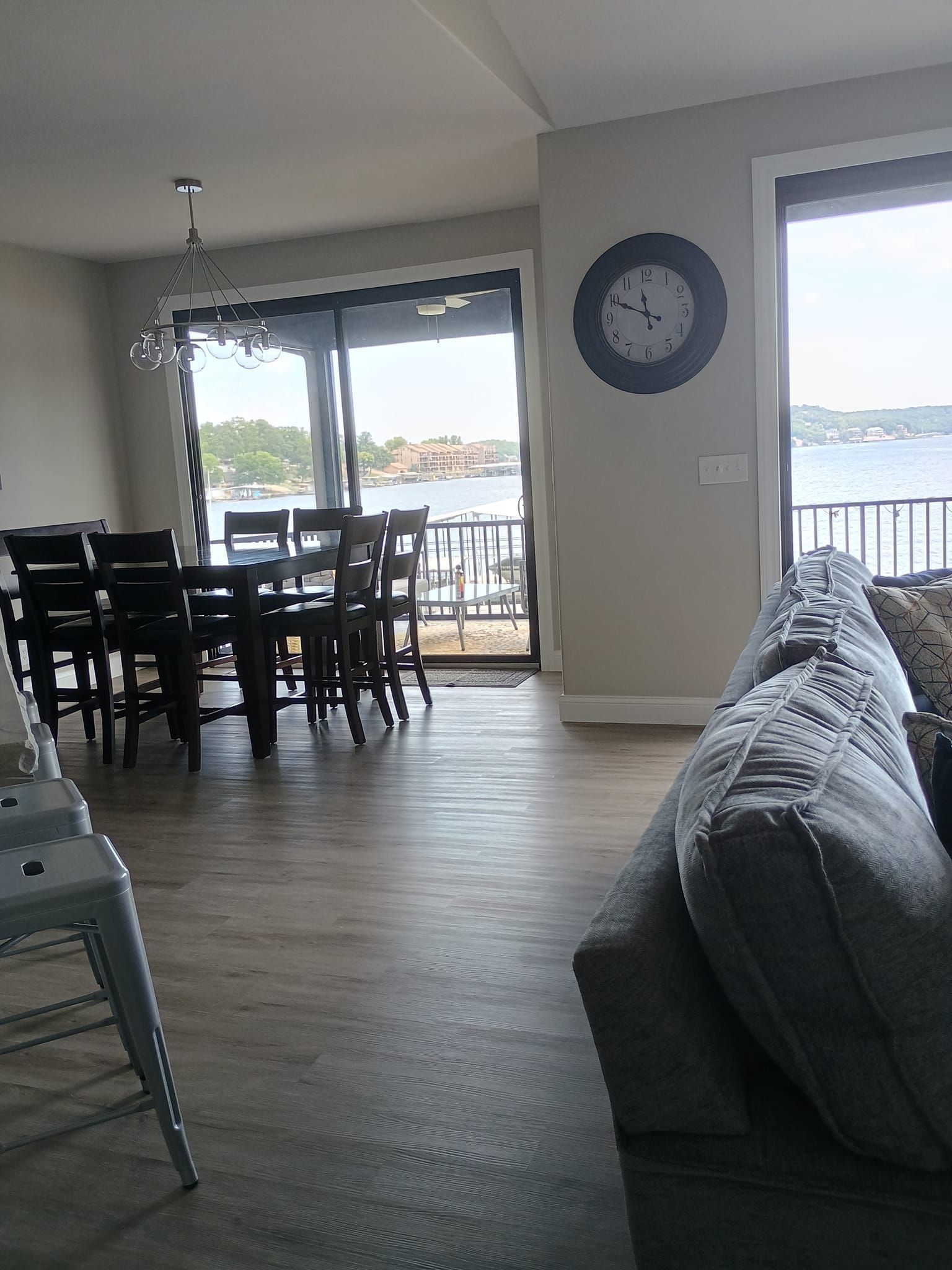Dining area with table, chairs, and lake view through sliding glass doors; clock on the wall.