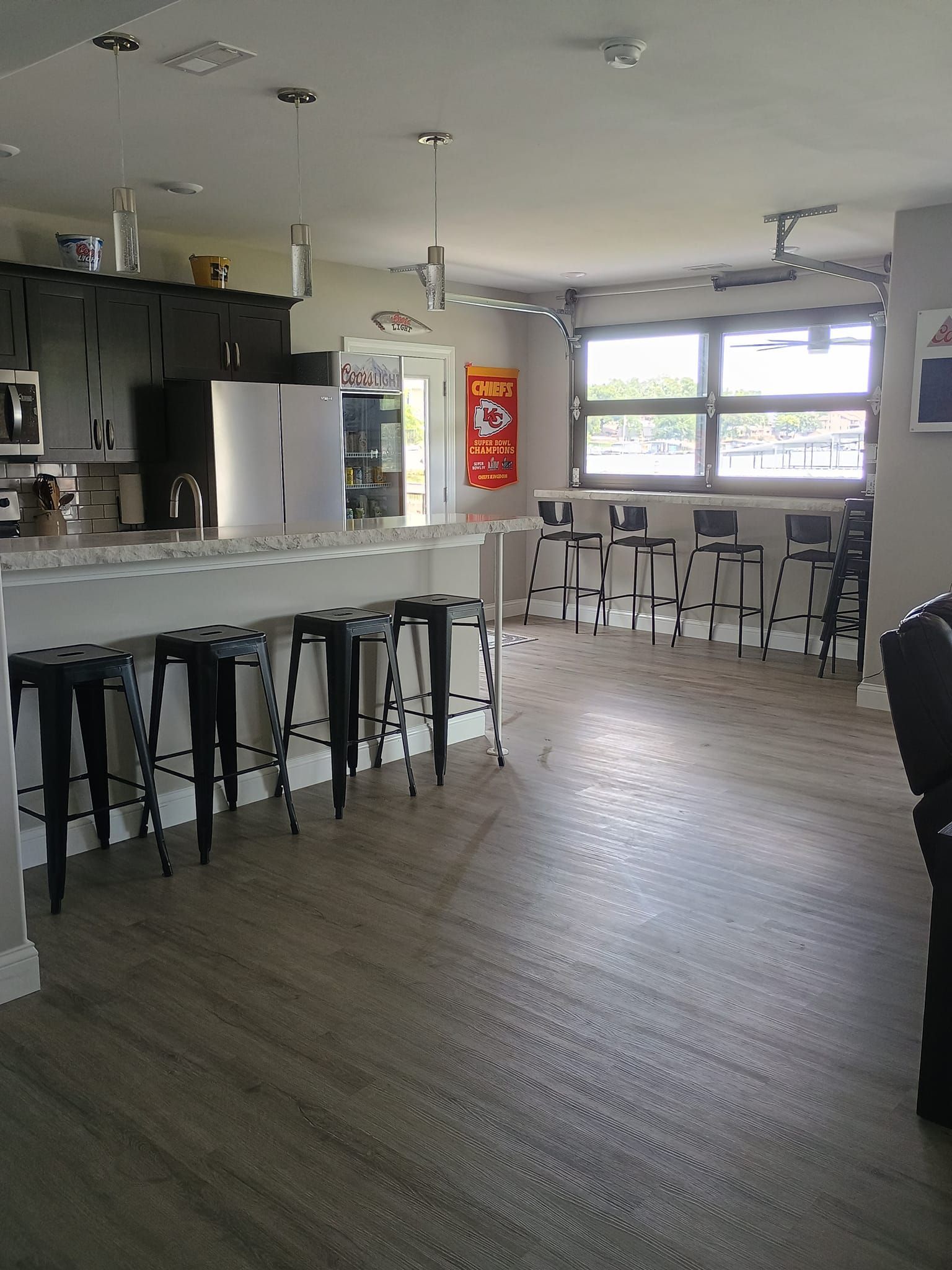 Kitchen area with a counter and stools, a window, and wood-look flooring.