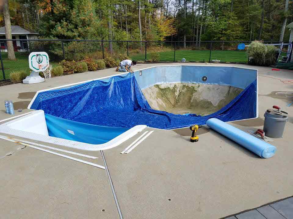 Adding a dark blue plastic cover to the ground - Pool Installation in Raynham. MA