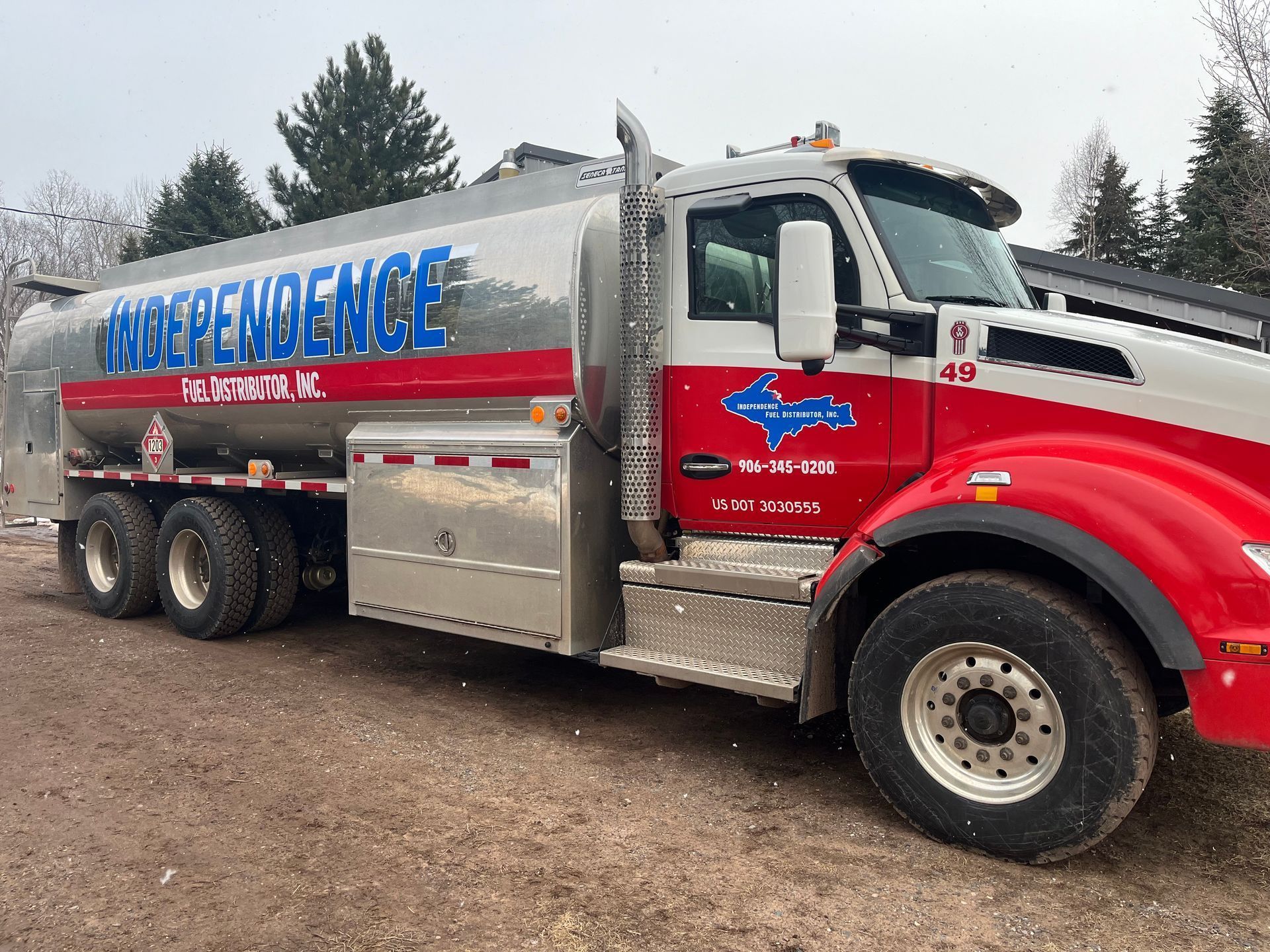 A silver and red Independence Oil fuel tanker truck parked outdoors. The truck has a large silver tank and red cab.