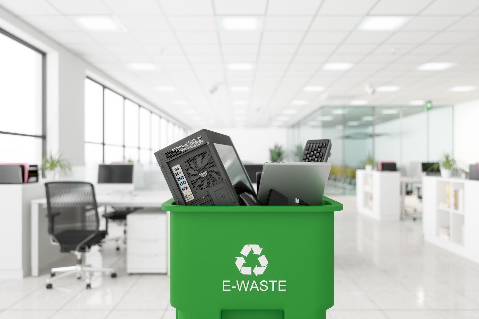 Electronic wastes are collected in a garbage bin with the e-waste symbol on it in an office.