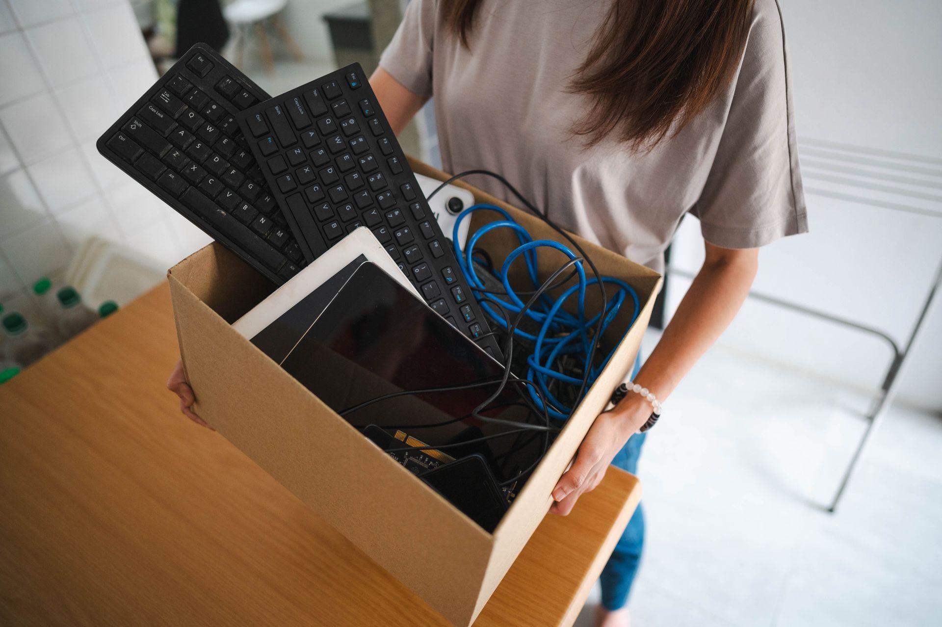 ITAD professional woman holding cardboard box with electronic waste for secure recycling.
