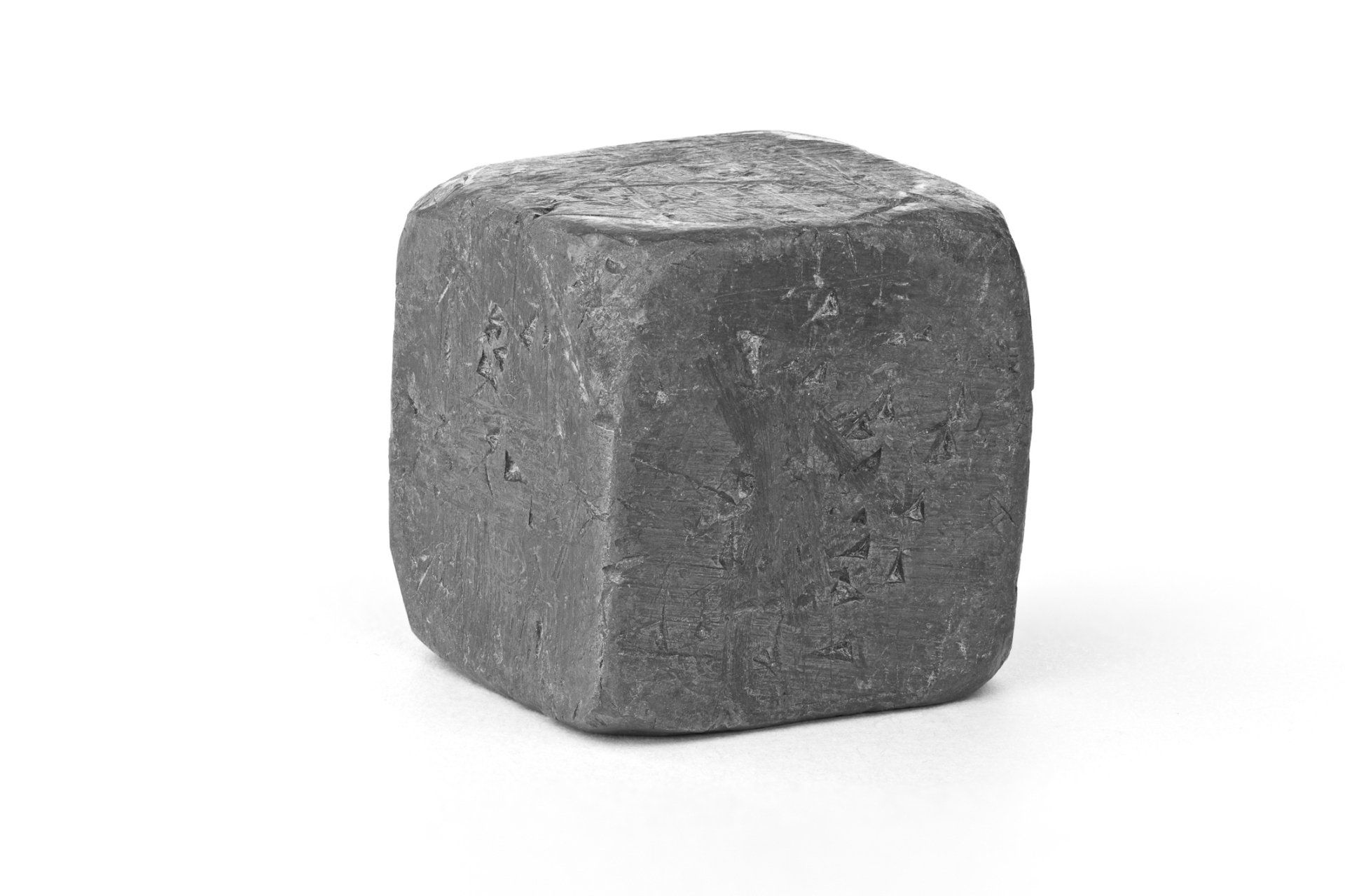 A black cube is sitting on a white surface.