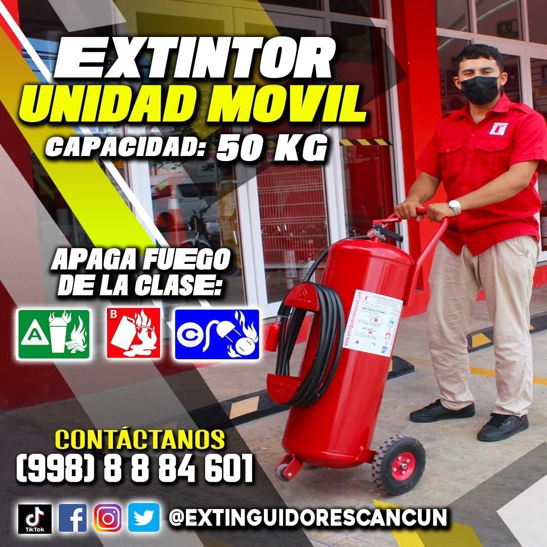 Un hombre con máscara empuja un extintor rojo sobre ruedas