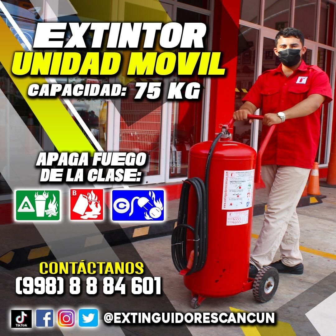 Un hombre con máscara empuja un extintor rojo sobre ruedas