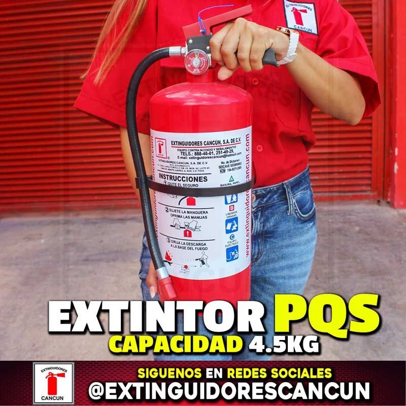 Una mujer con una camisa roja sostiene un extintor de incendios rojo.
