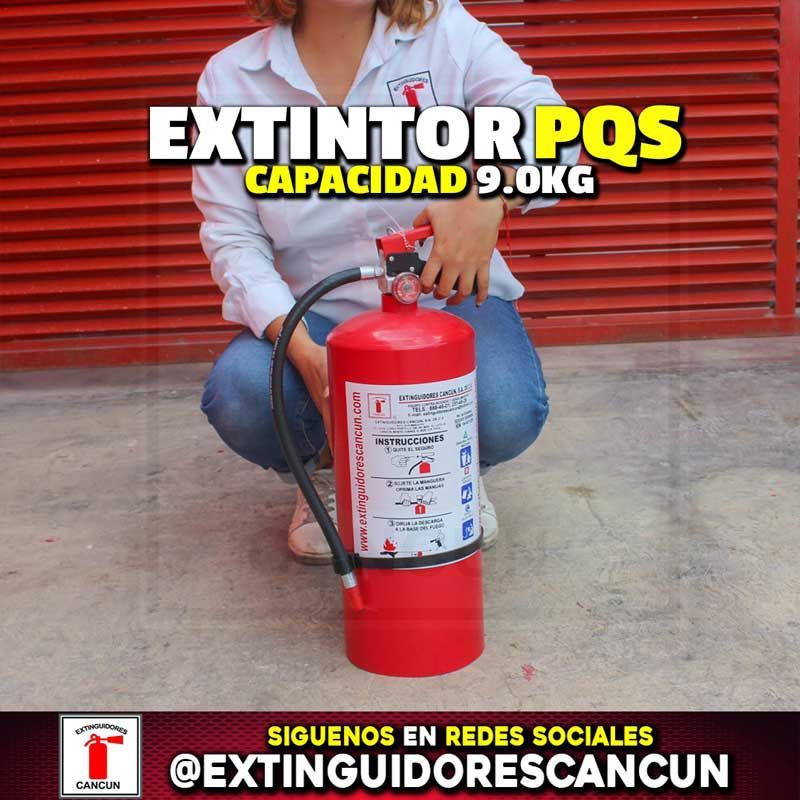 Una mujer está arrodillada junto a un extintor rojo.