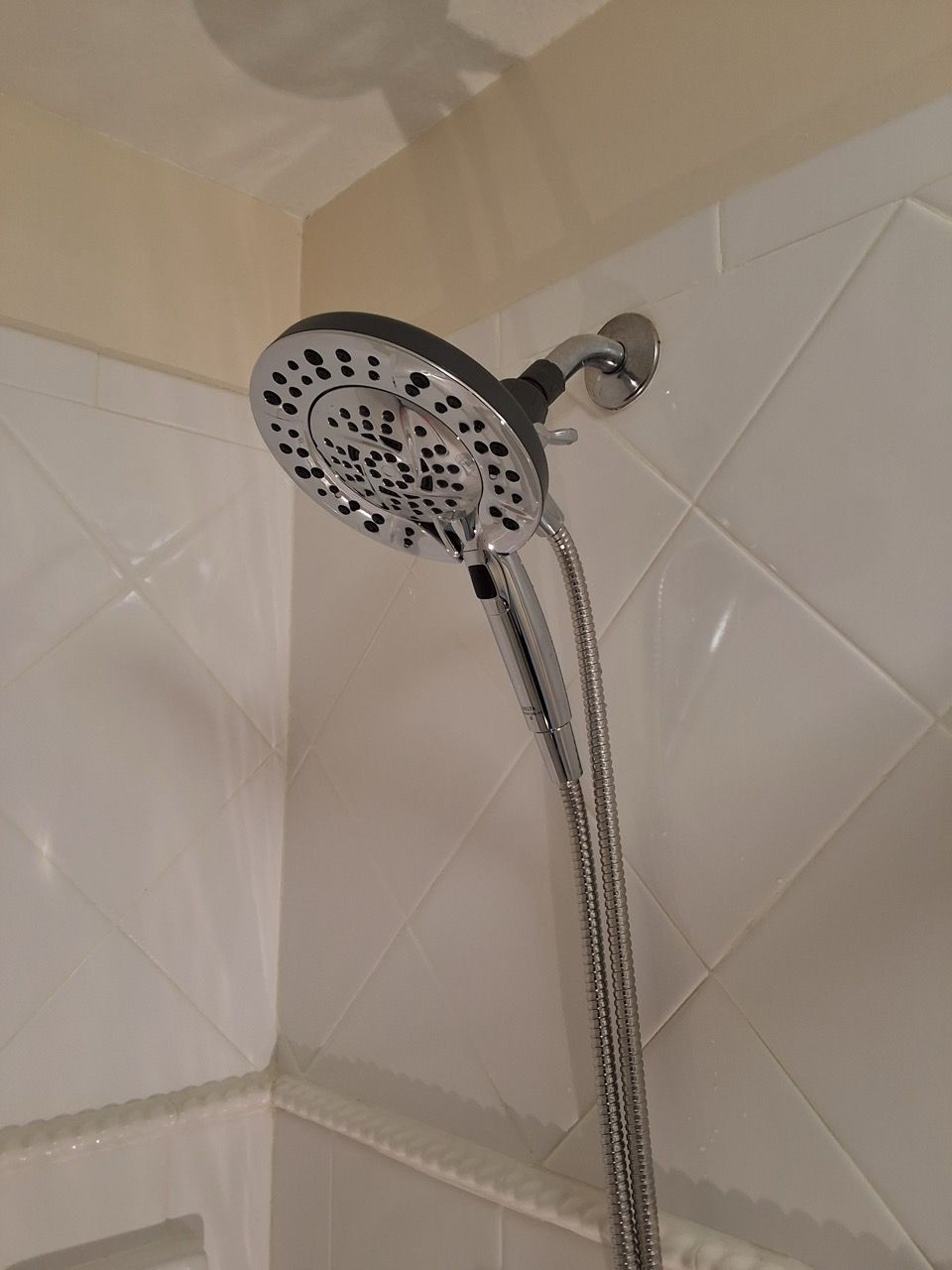 Chrome showerhead on a tiled bathroom wall, spraying water downward