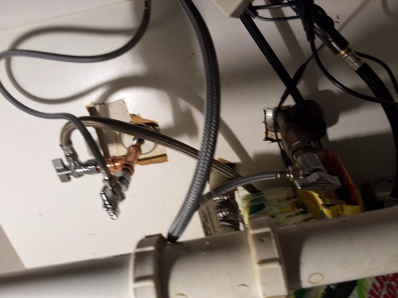 Under-sink plumbing with two shutoff valves and hoses on a wall-mounted fixture