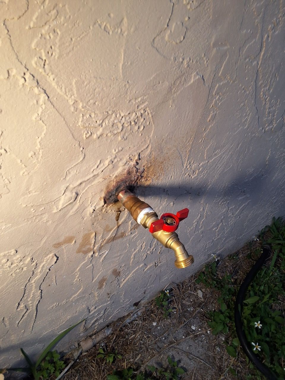 Red and yellow toy figure on a textured wall, with a dark stain and debris below.