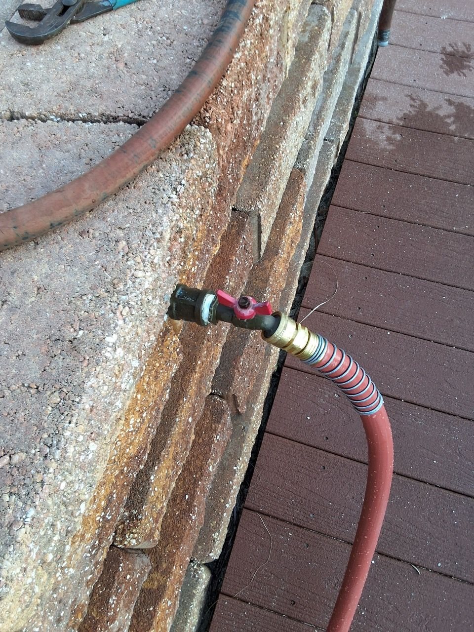 Close-up of a rusted roof pipe fitting with a brown hose attached beside shingles.