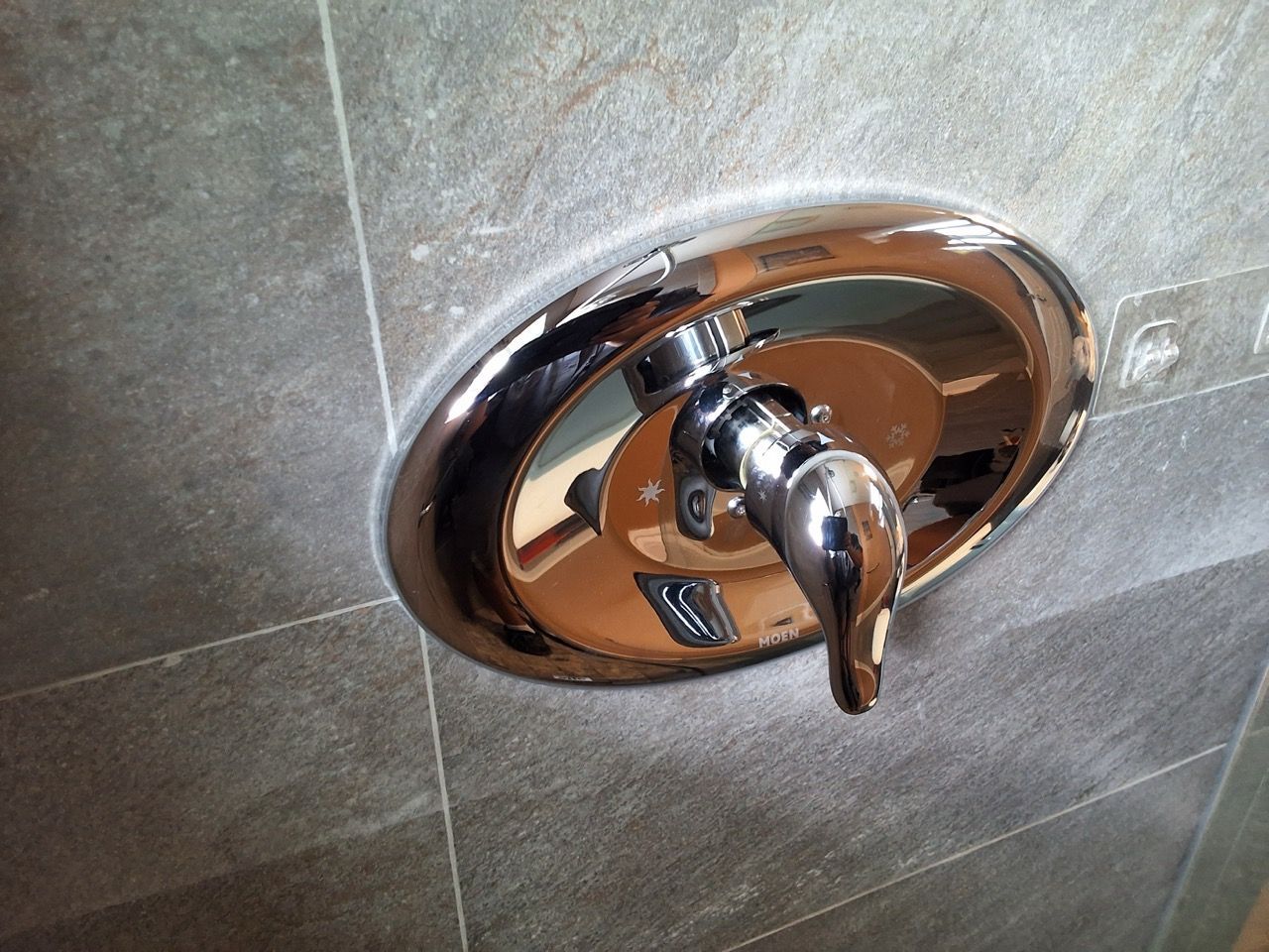 Chrome shower control valve on a tiled bathroom wall