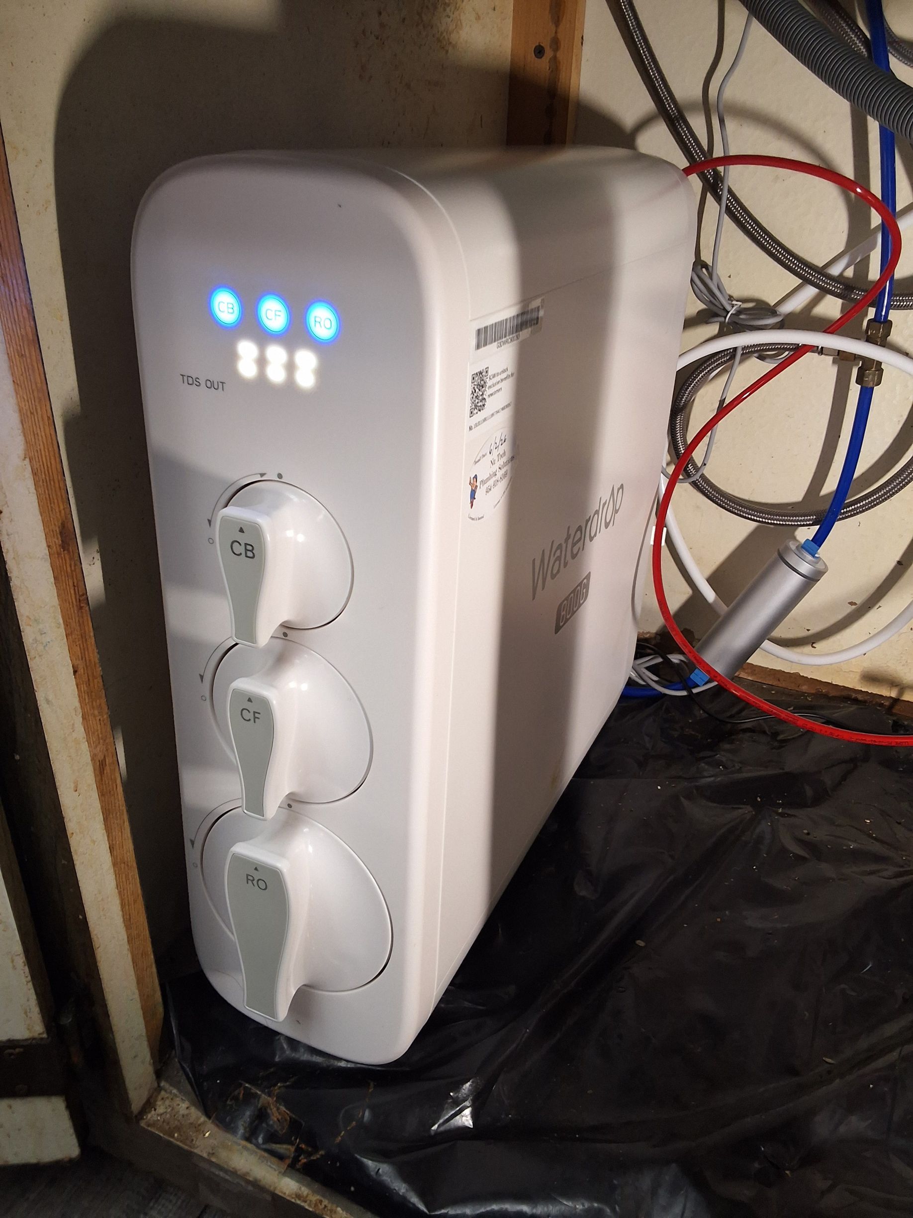 White three-outlet power strip with blue LEDs plugged into a cluttered wall area.