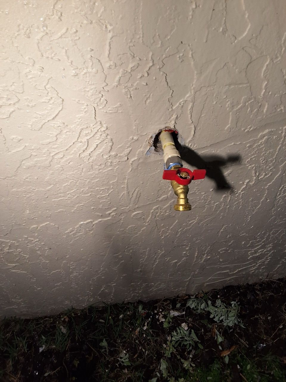 Small red-and-black figurine hanging from a textured ceiling, near the bottom edge of the frame